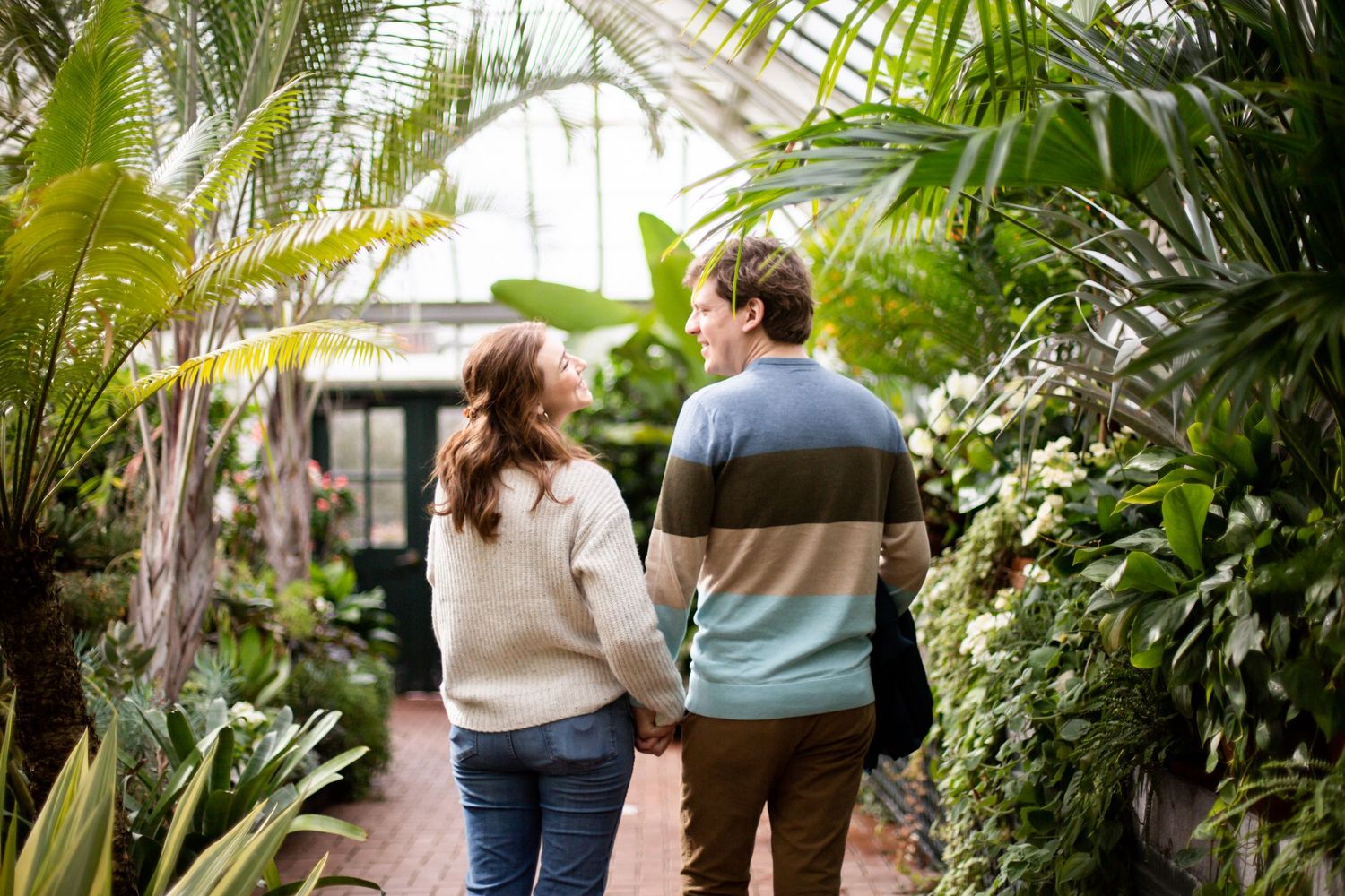 A woman and a man walking through a greenhouse