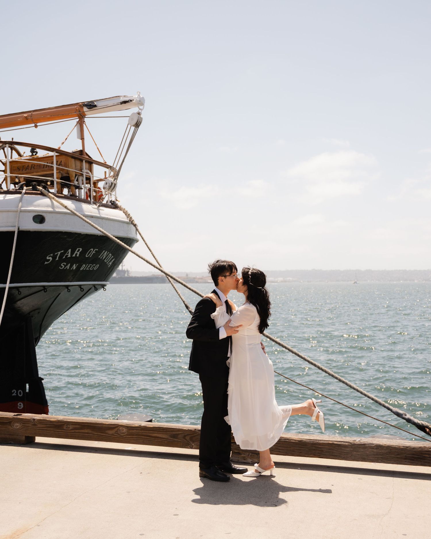 Couple kissing on dock beside Star of India tall ship in San Diego bay.