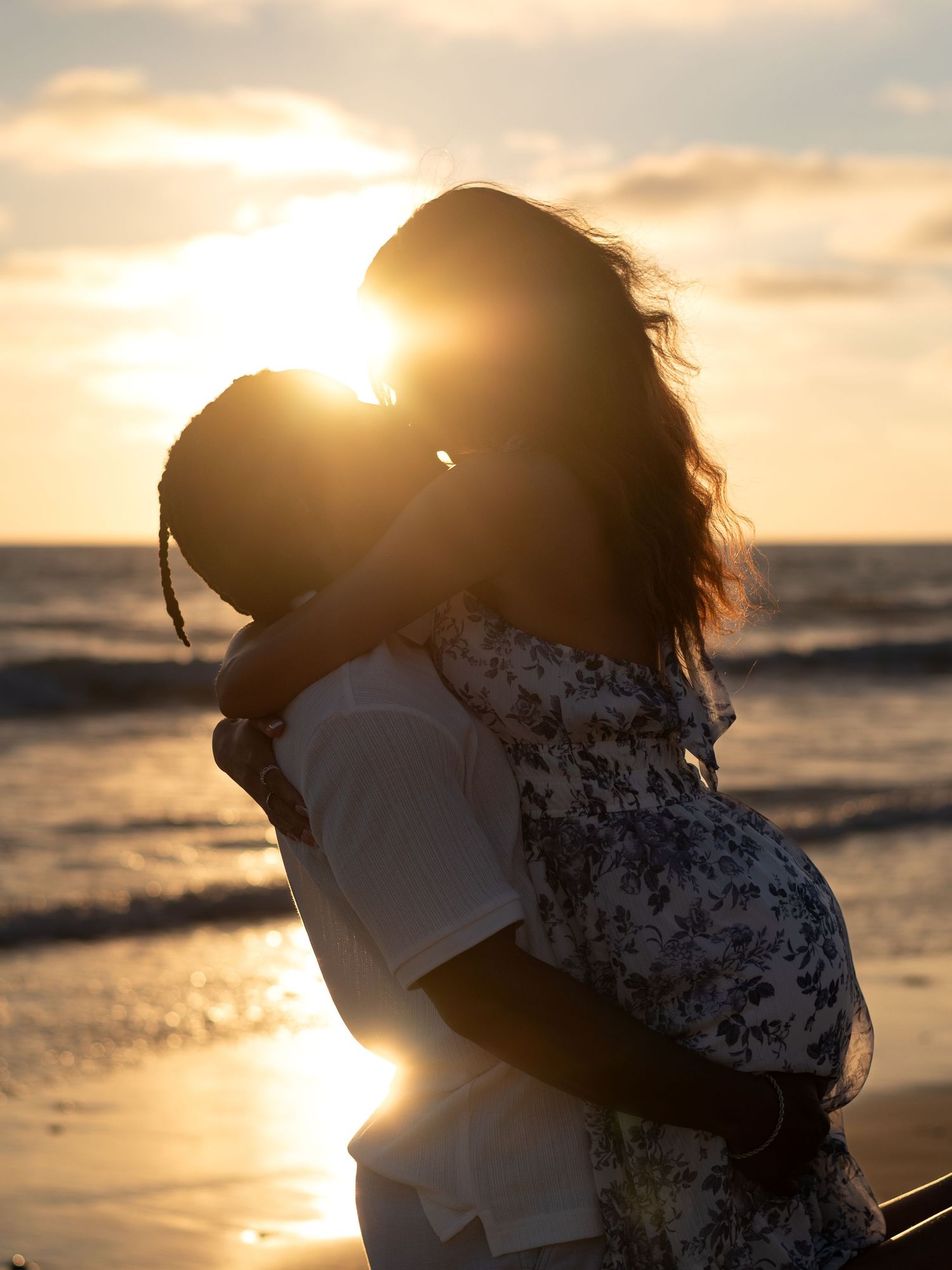 Couple sharing romantic kiss on beach at stunning golden sunset.