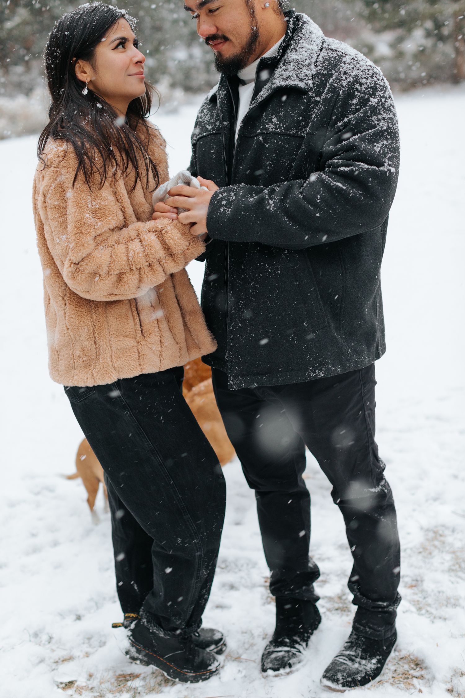 A romantic winter photoshoot with a couple embracing in the falling snow.