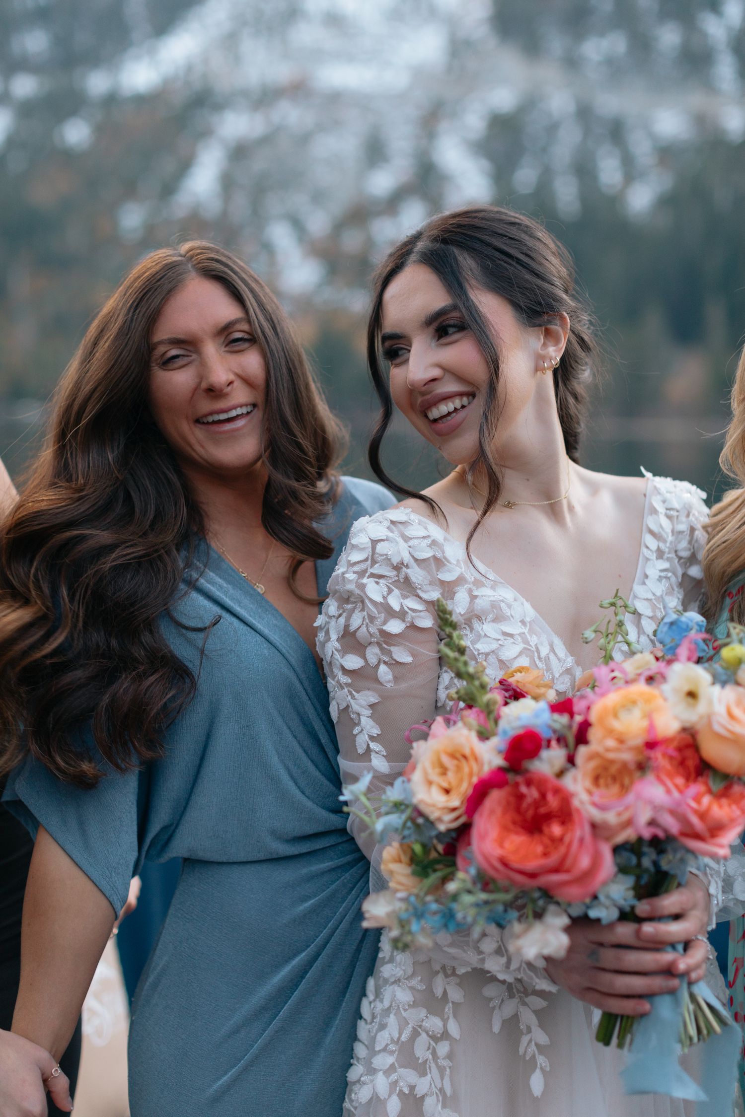 Two people share a joyful moment while holding a vibrant bouquet of coral and pink flowers.