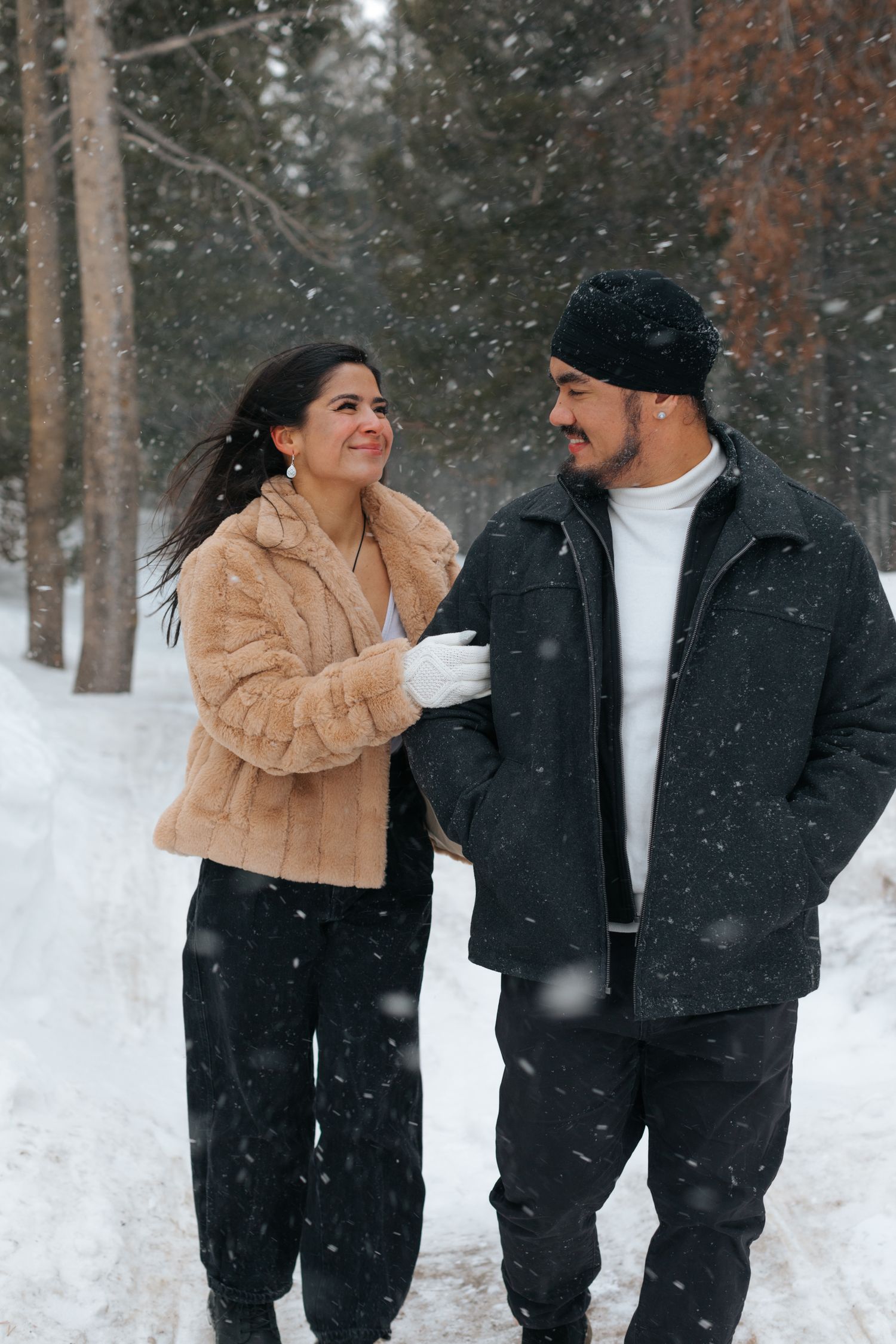 Romantic winter photoshoot in a snow-covered forest with pine trees.