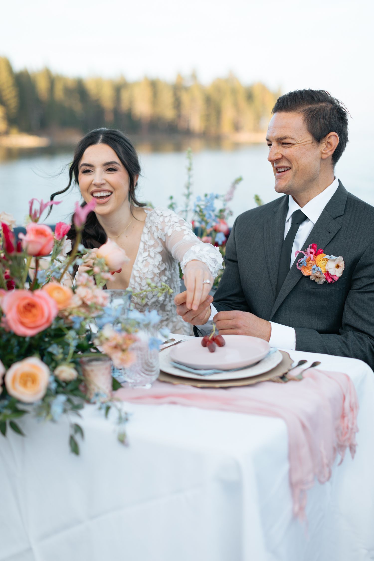 Elegant lakeside wedding reception with colorful floral centerpiece.