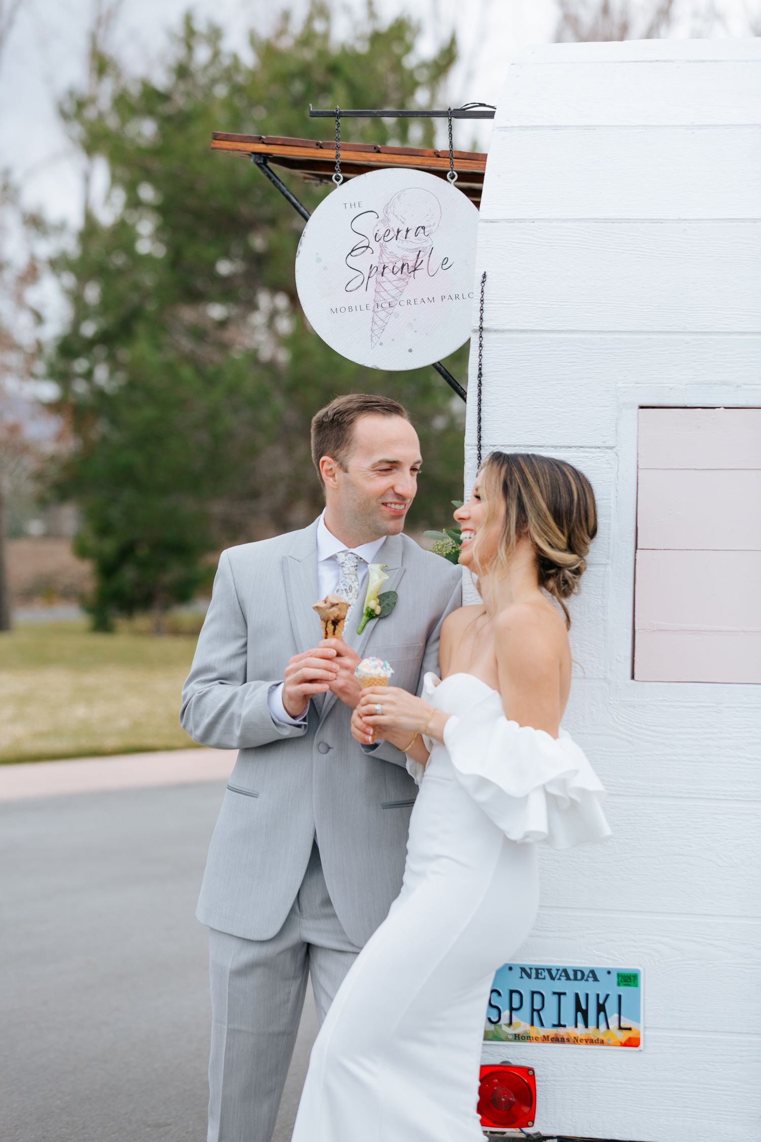 Newlyweds sharing sweet moments by ice cream truck with Sprinkle sign.
