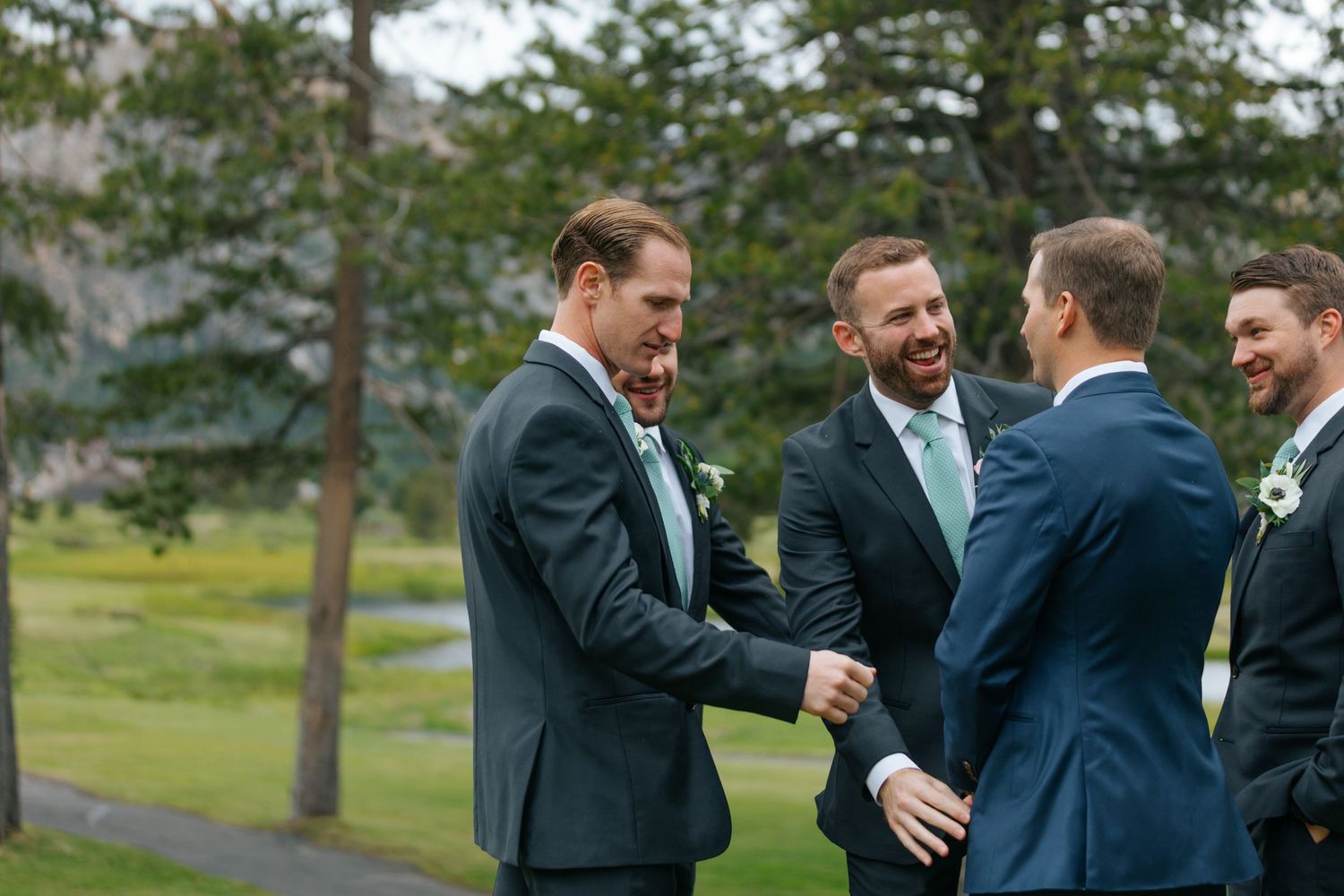 Groomsmen share laughs and hugs during outdoor wedding celebrations.