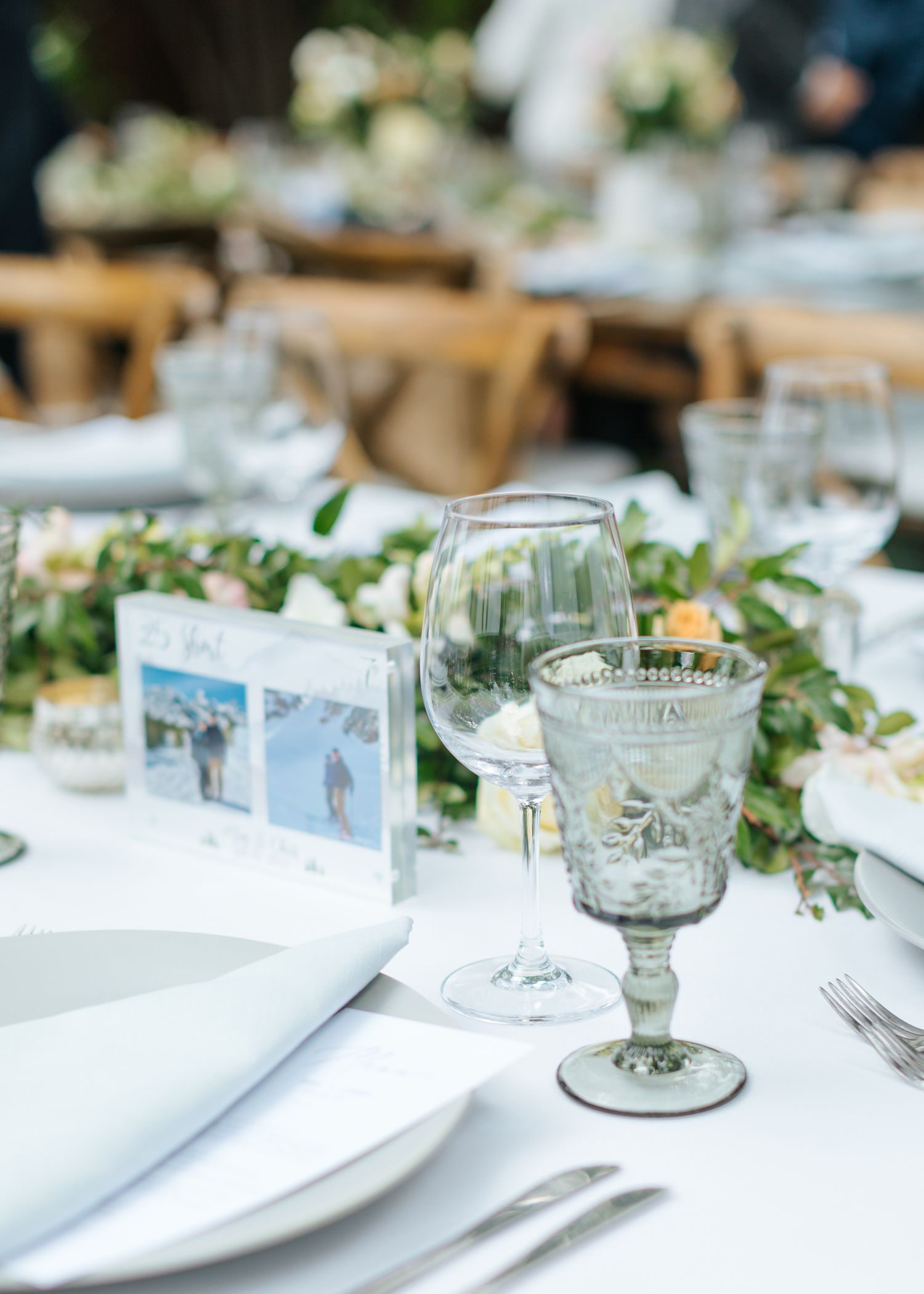 Elegant wedding reception table setting with white linens and greenery decorations.