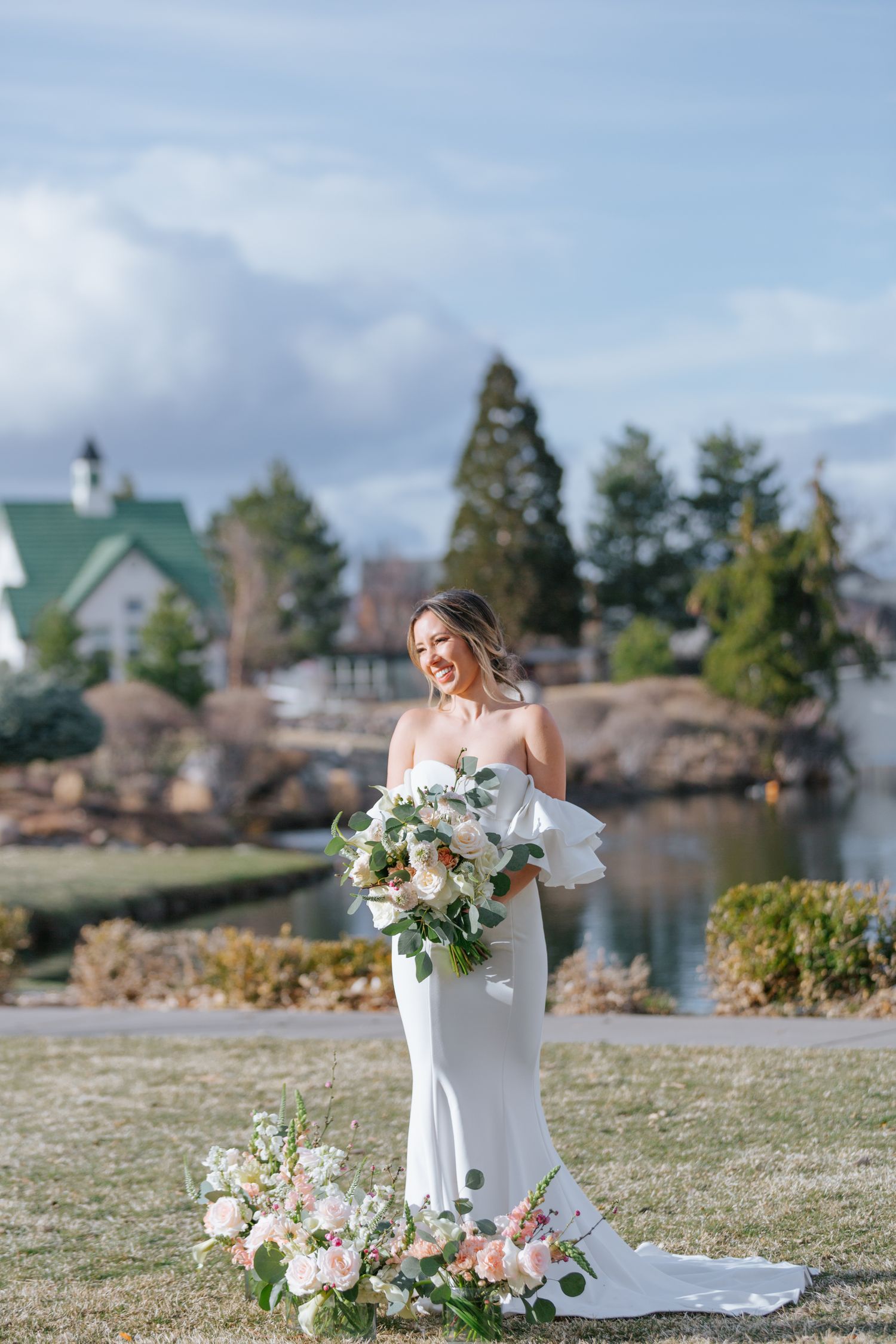 Wedding photography with floral bouquets on grassy lawn overlooking waterfront.