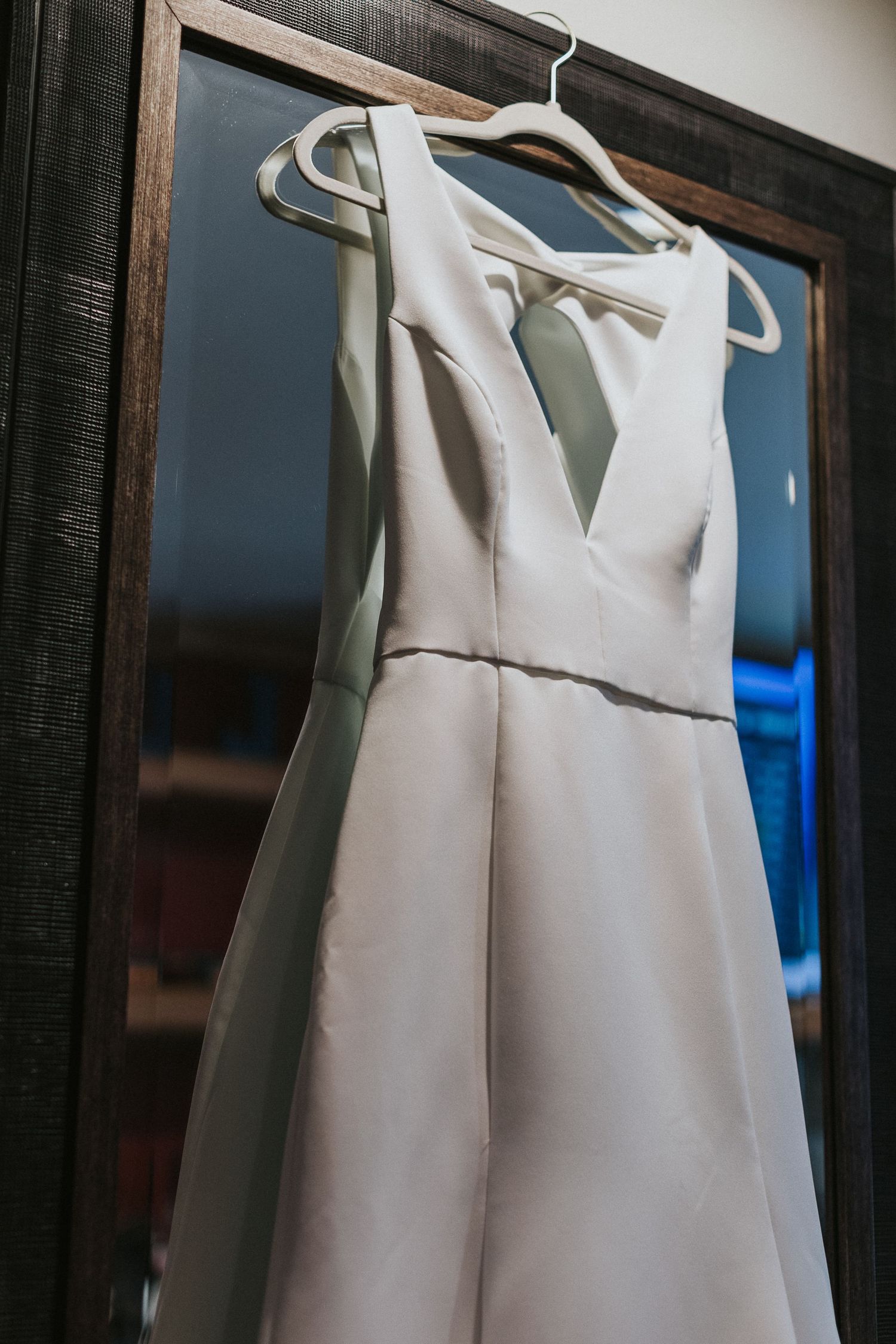 White dress shirts hanging neatly on wooden hangers against a dark wall.