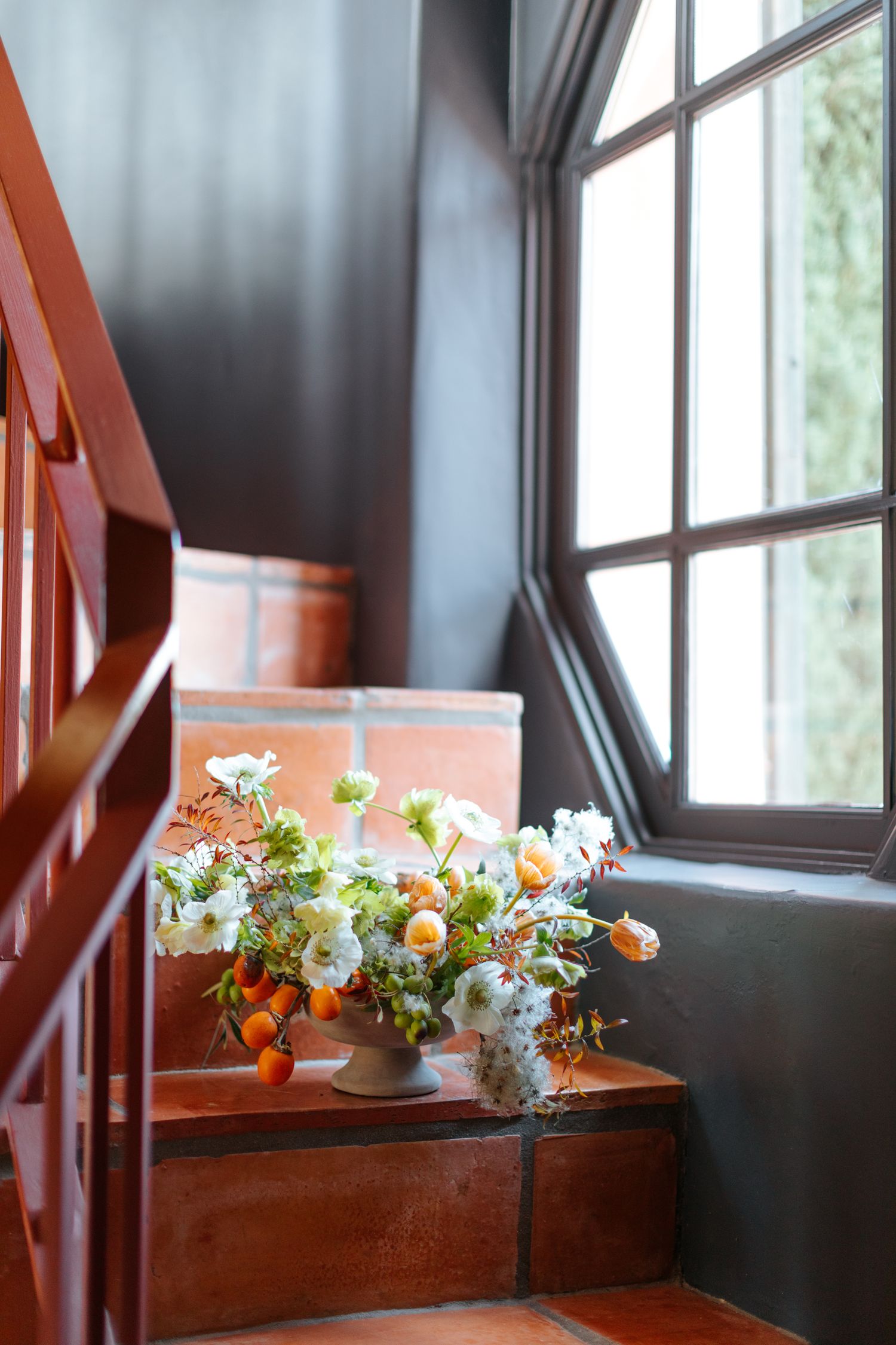 Delicate floral arrangements with peach and white flowers decorating wooden stairs.