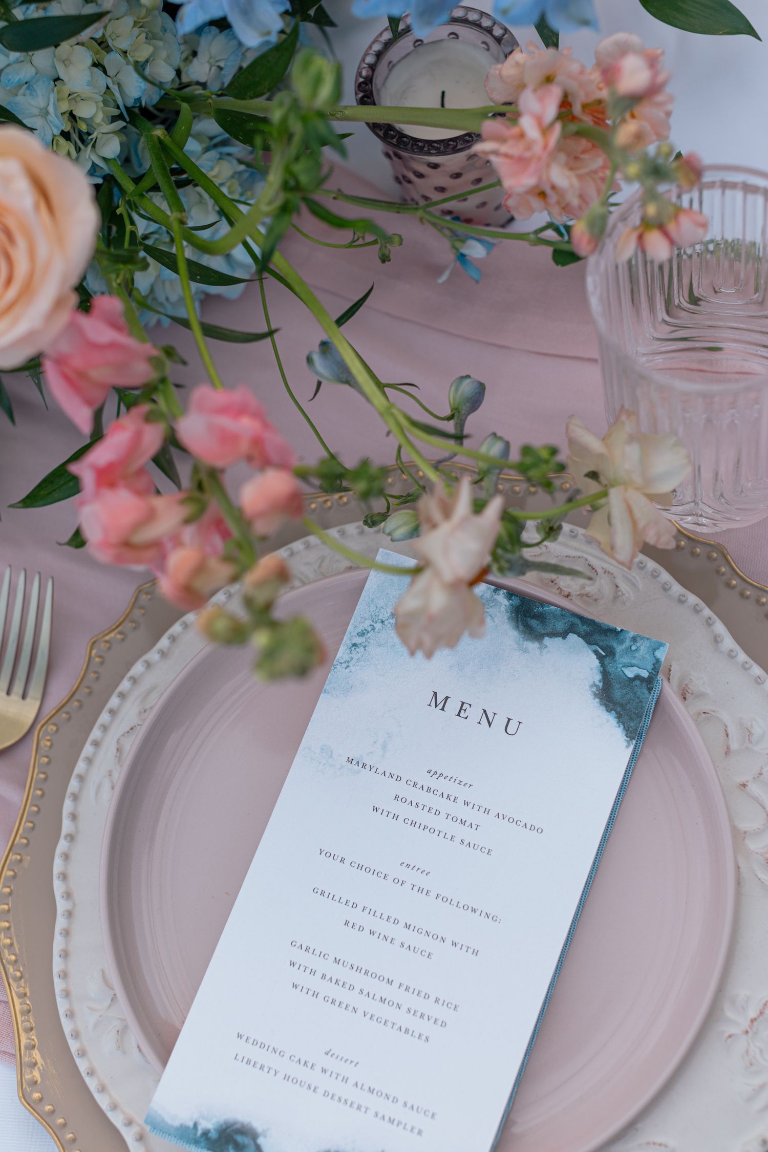Wedding reception place setting with menu card and delicate pink floral decorations.