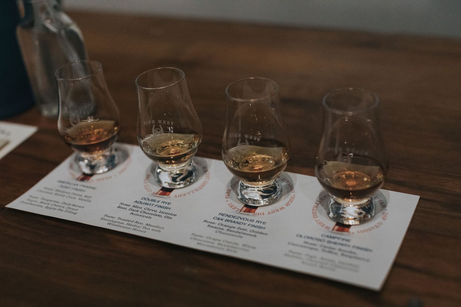 Whiskey tasting setup with multiple glasses and tasting notes on a wooden table.