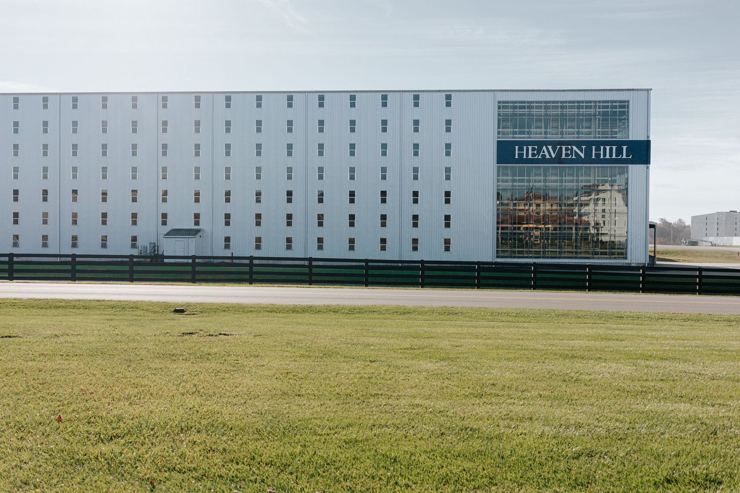 Long white industrial building with Heaven Hill branding against green lawn.