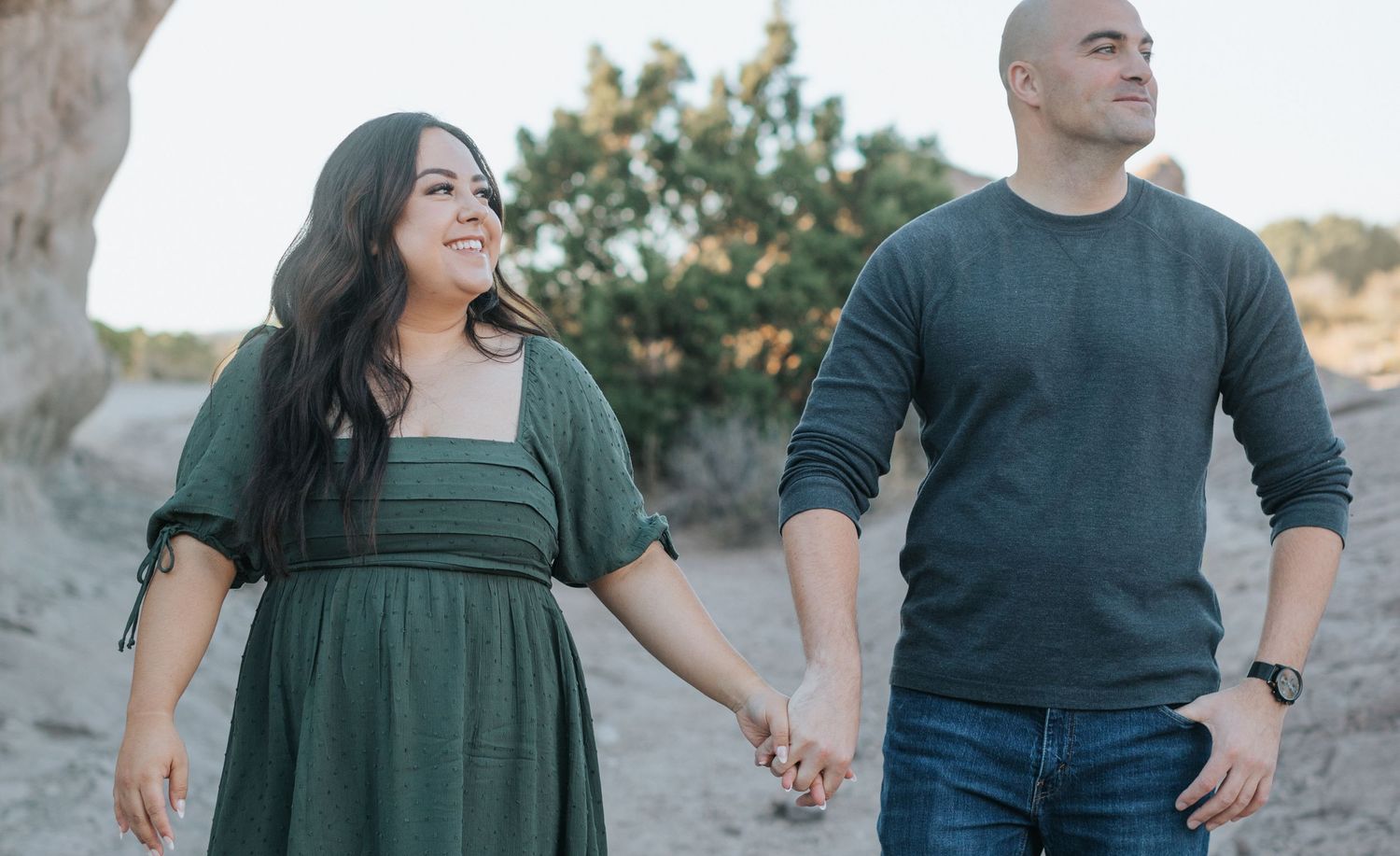 A couple walks hand in hand during their desert engagement photo session.