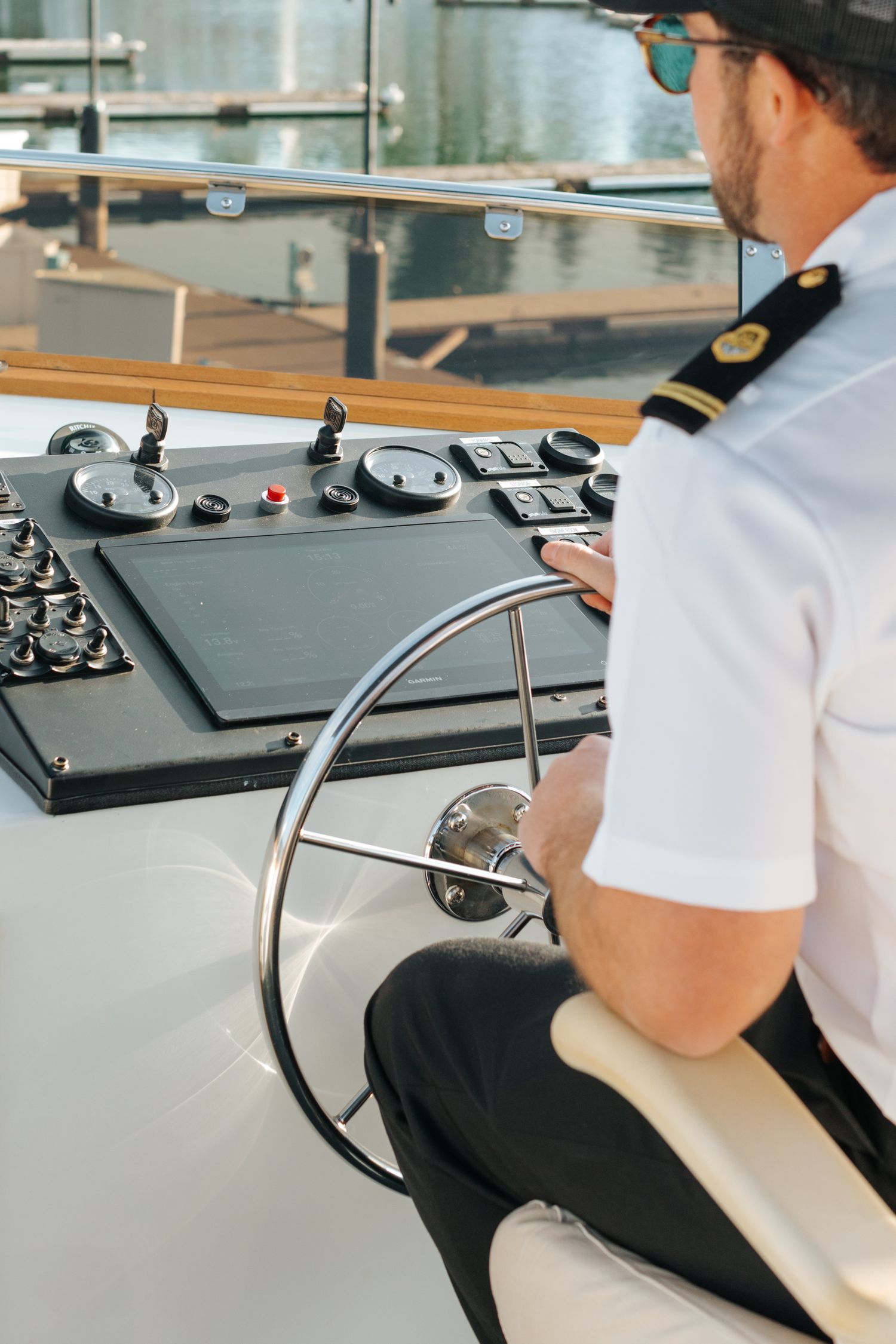 Person steering a boat from captain's chair with navigation controls visible.