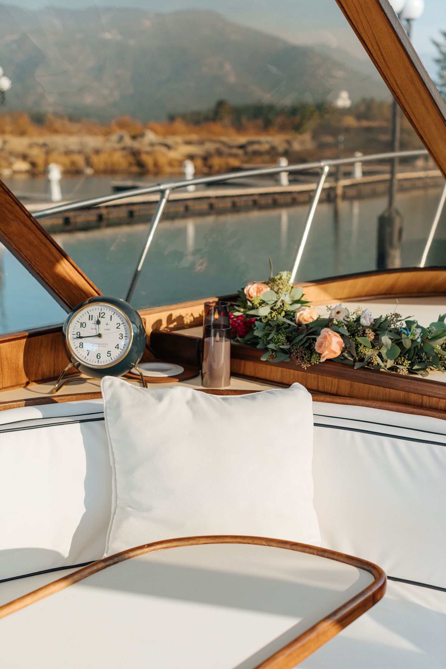 Interior of a luxury yacht cabin with white cushions, wooden trim, and decorative floral arrangements.