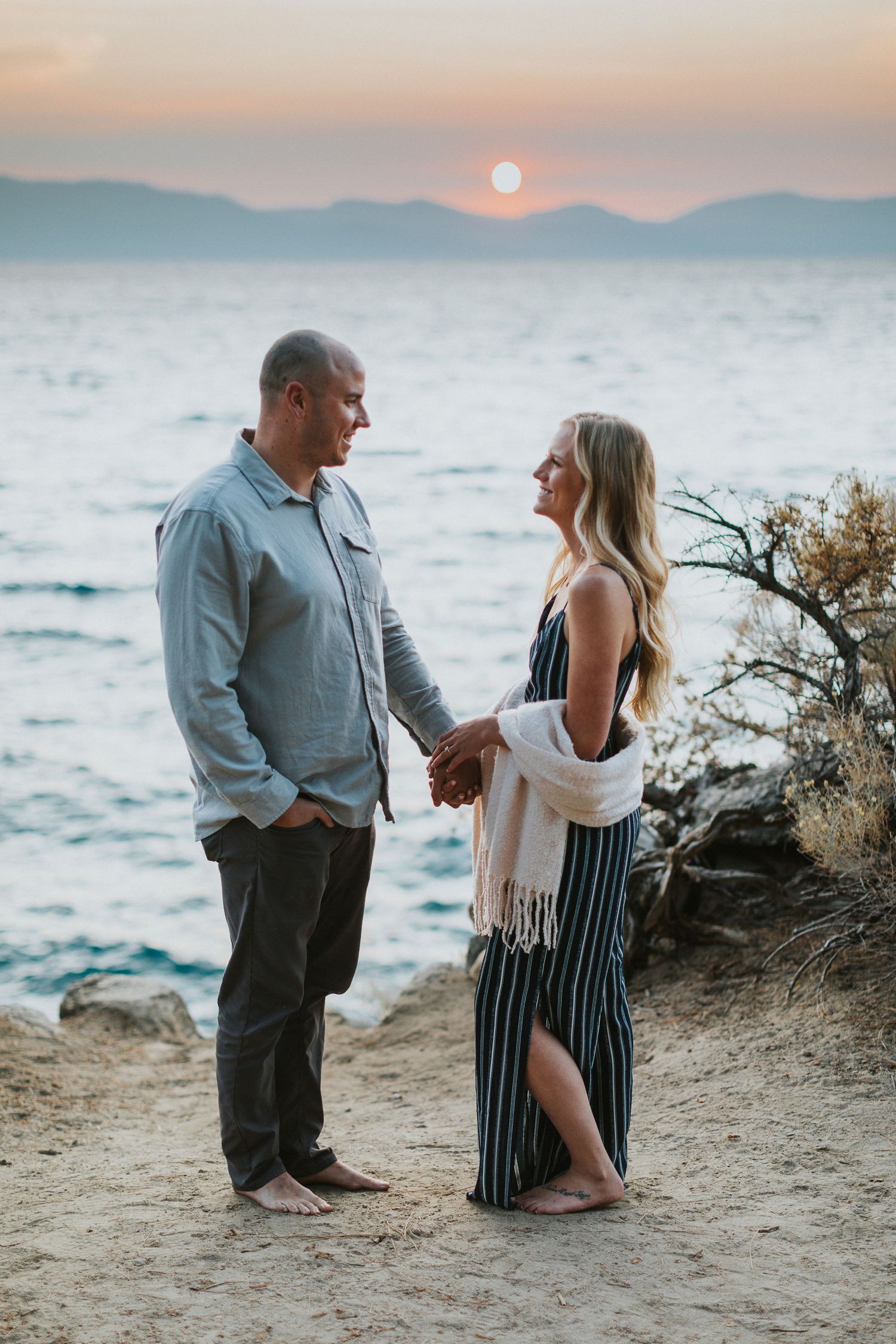 Couple shares romantic moment on coastal cliff during sunset.