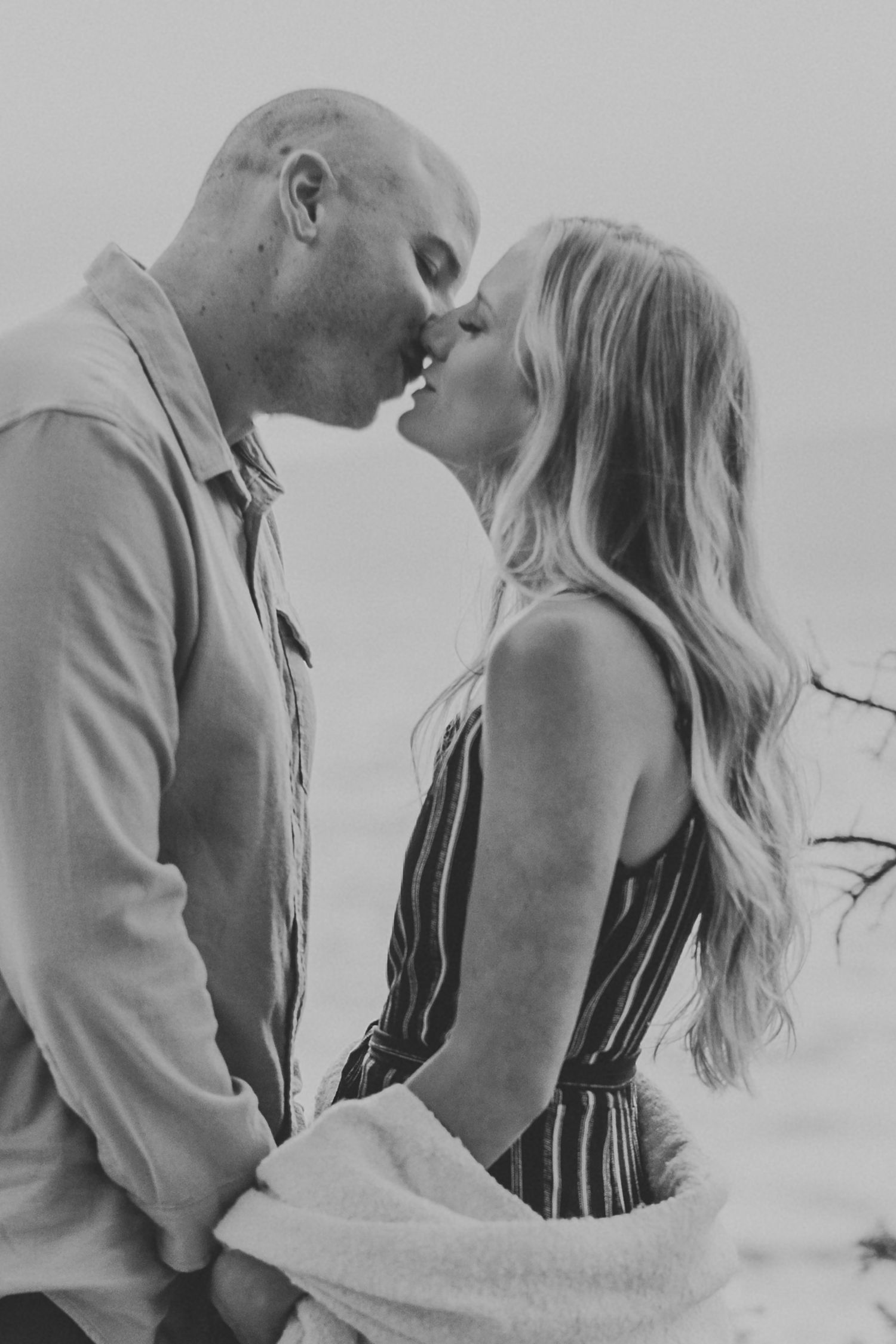 Black and white portrait of a couple sharing an intimate moment outdoors.