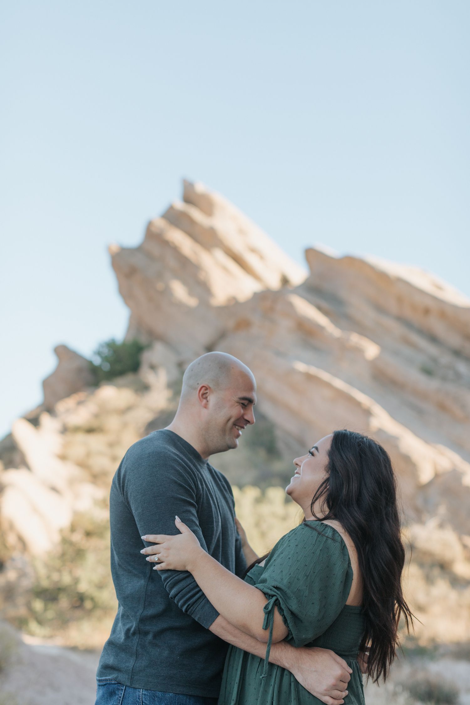 A couple embraces and laughs during their desert engagement photo session.
