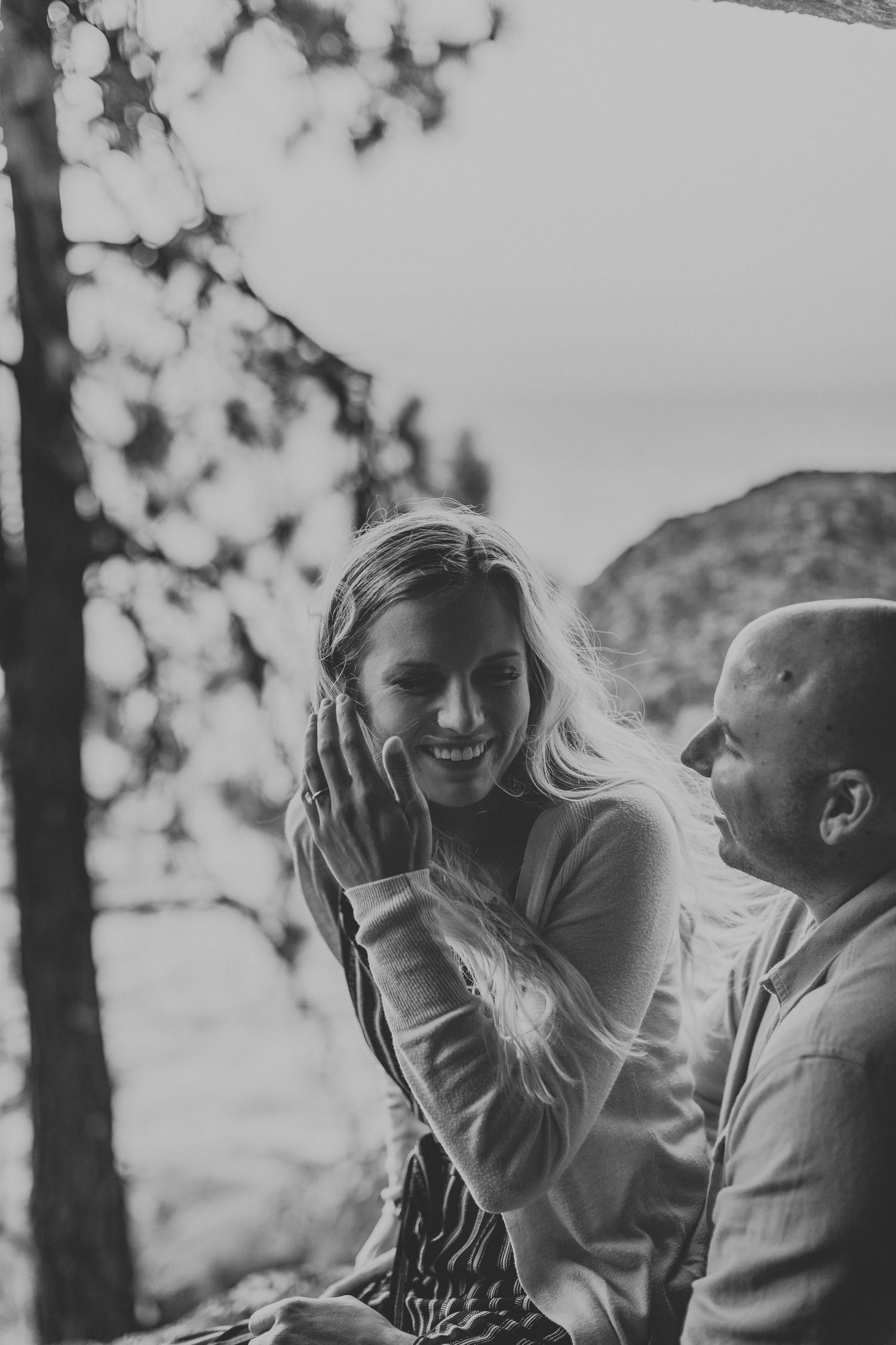Candid black and white photo of a couple sharing joyful laughter outdoors.