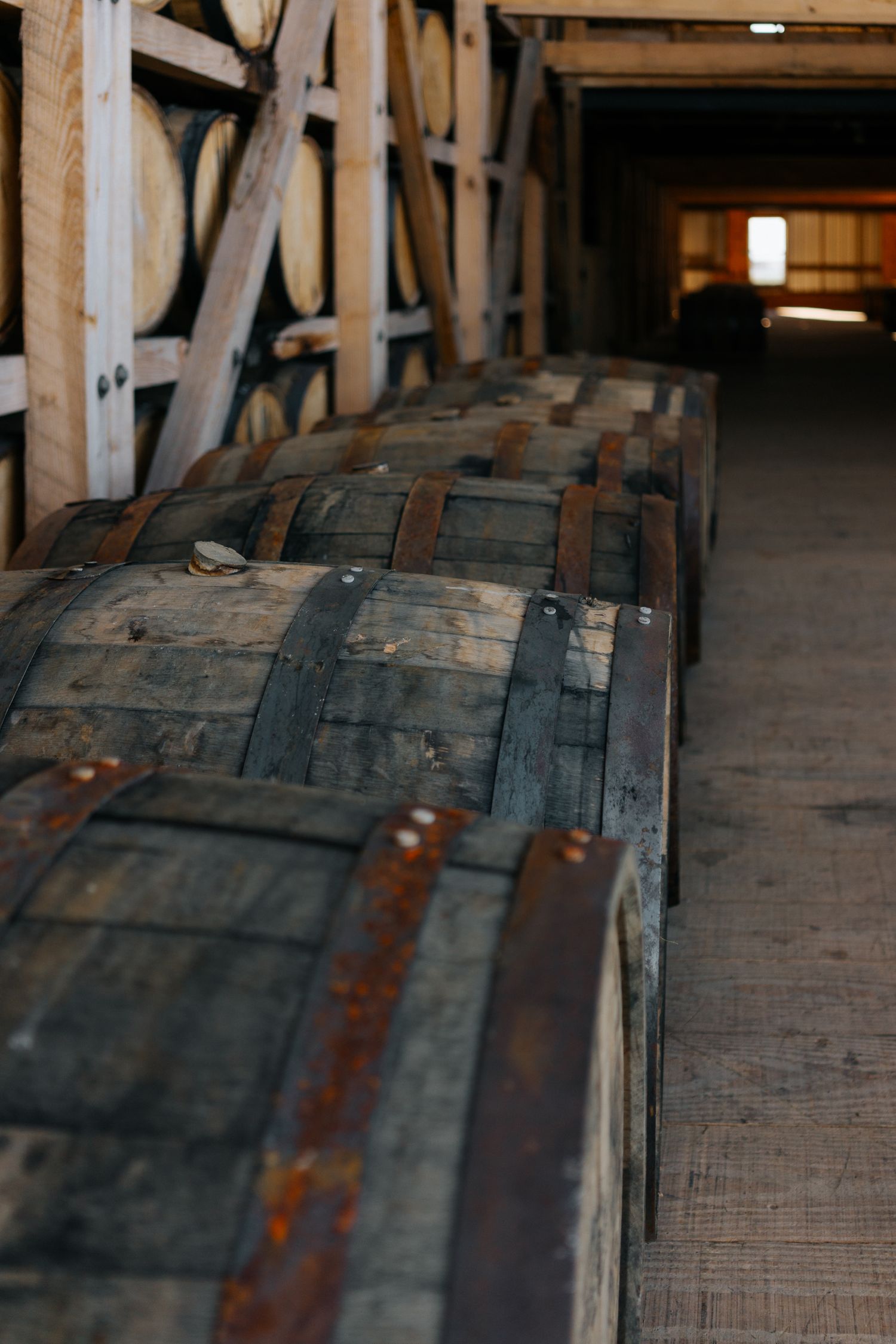 Close-up view of aging bourbon barrels lined up in a rickhouse.