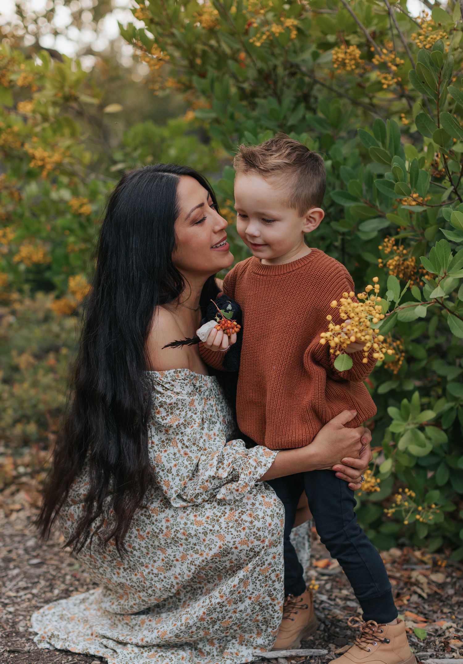 A tender moment captured in autumn as parent and child share affectionate moments among golden foliage and greenery.