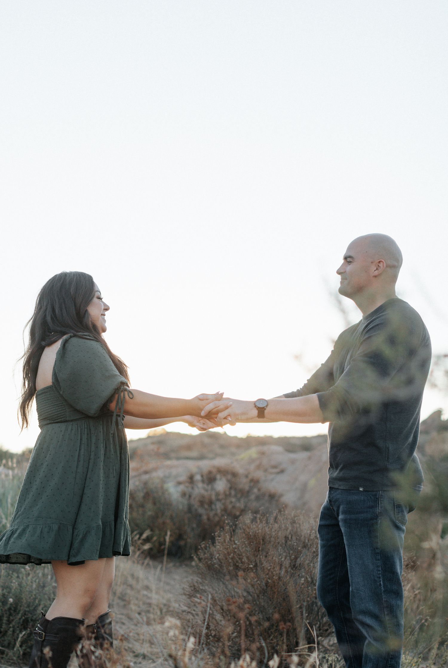 A couple dances playfully in a desert setting during golden hour.