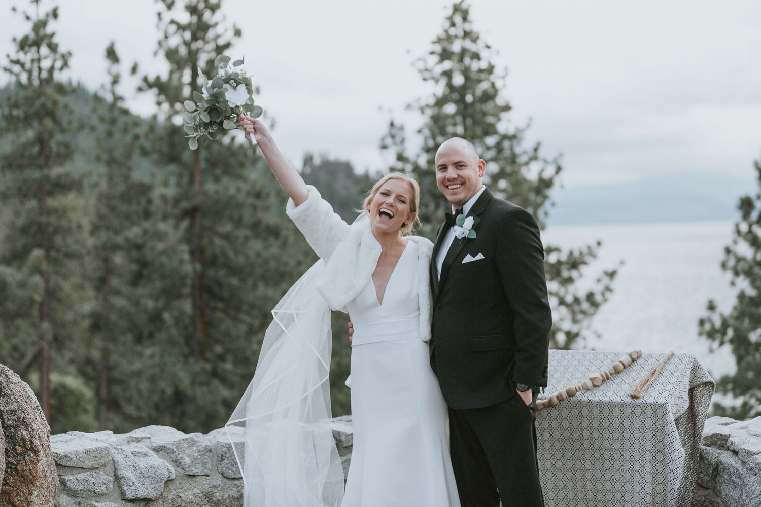 Wedding couple celebrates on mountain overlook with dramatic landscape views.