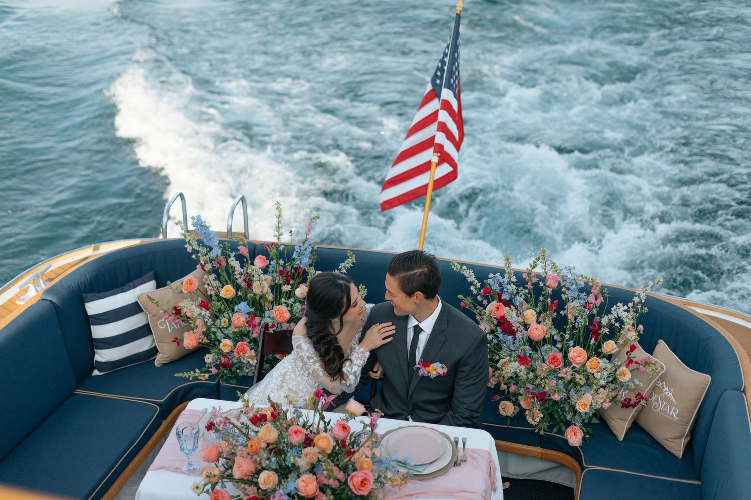 Romantic boat wedding setup with American flag and coral floral arrangements.