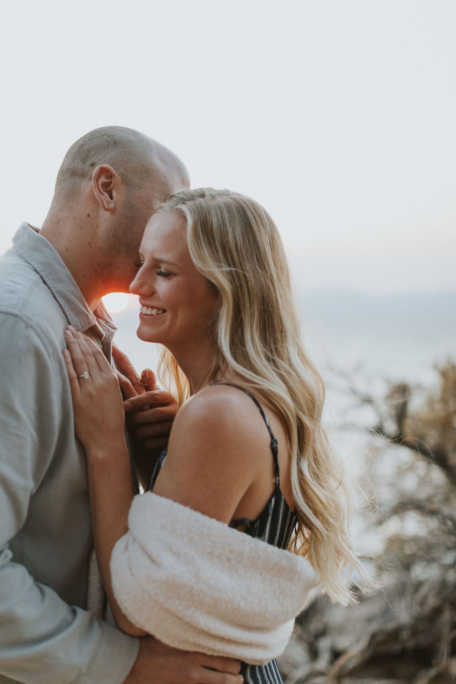Romantic couple sharing close embrace during sunset portrait session.