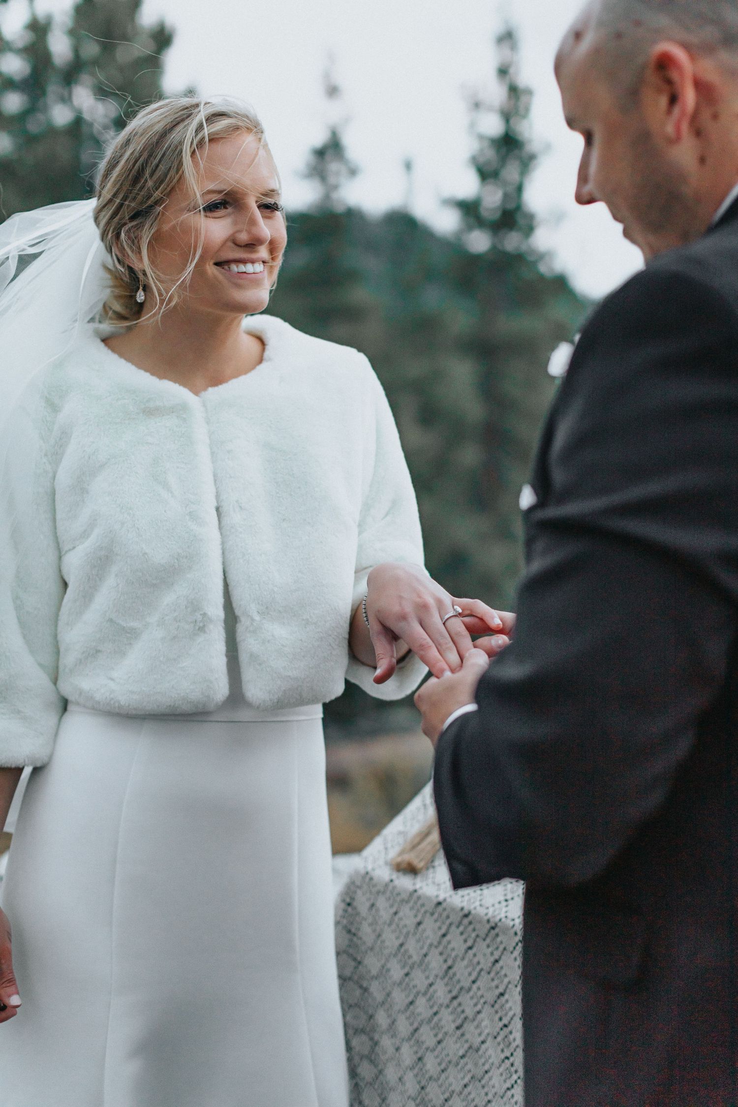 Couple in winter attire exchanging rings during an intimate outdoor ceremony.