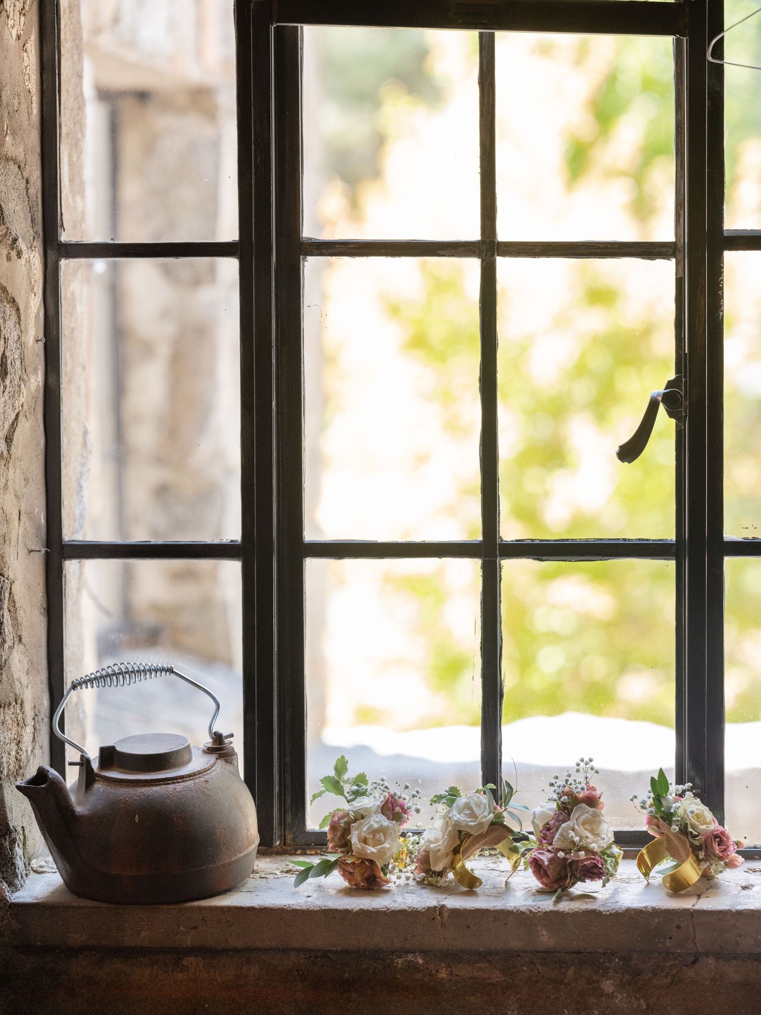 Rustic windowsill decorated with teapots and delicate flowers in vintage style.