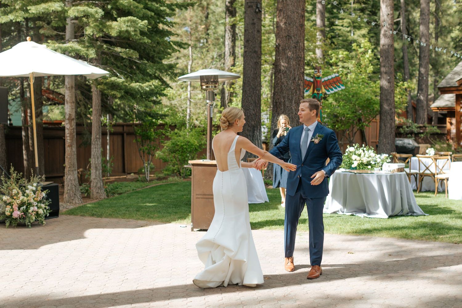 Outdoor wedding ceremony setup with white chairs and decorations among tall pine trees.