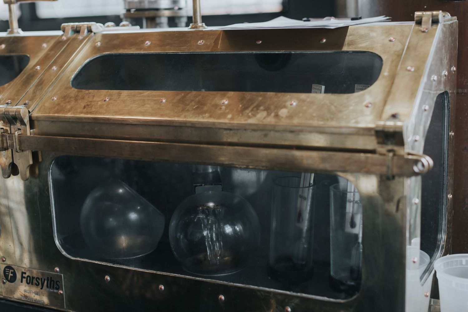 Industrial distillery equipment with copper and steel components in manufacturing setting.