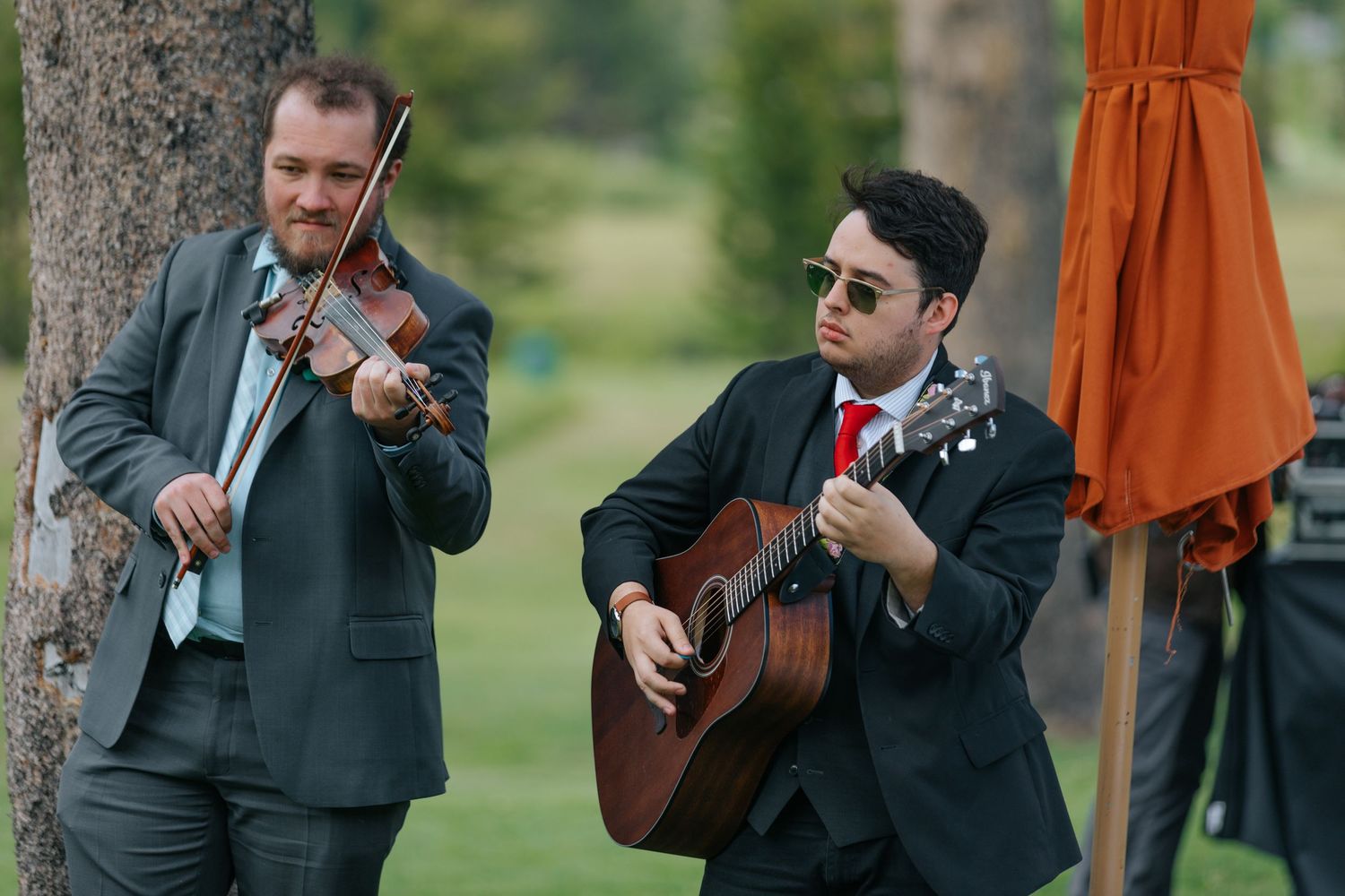Musicians play acoustic guitars during outdoor wedding ceremony.