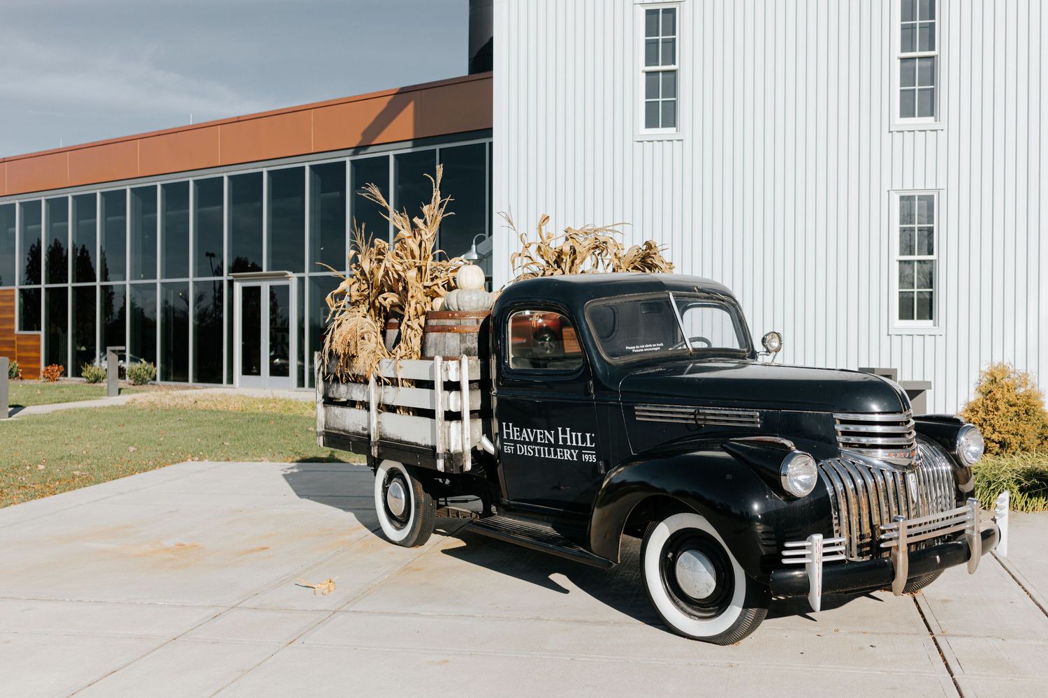 Vintage black truck parked outside white industrial building with classic architectural details.