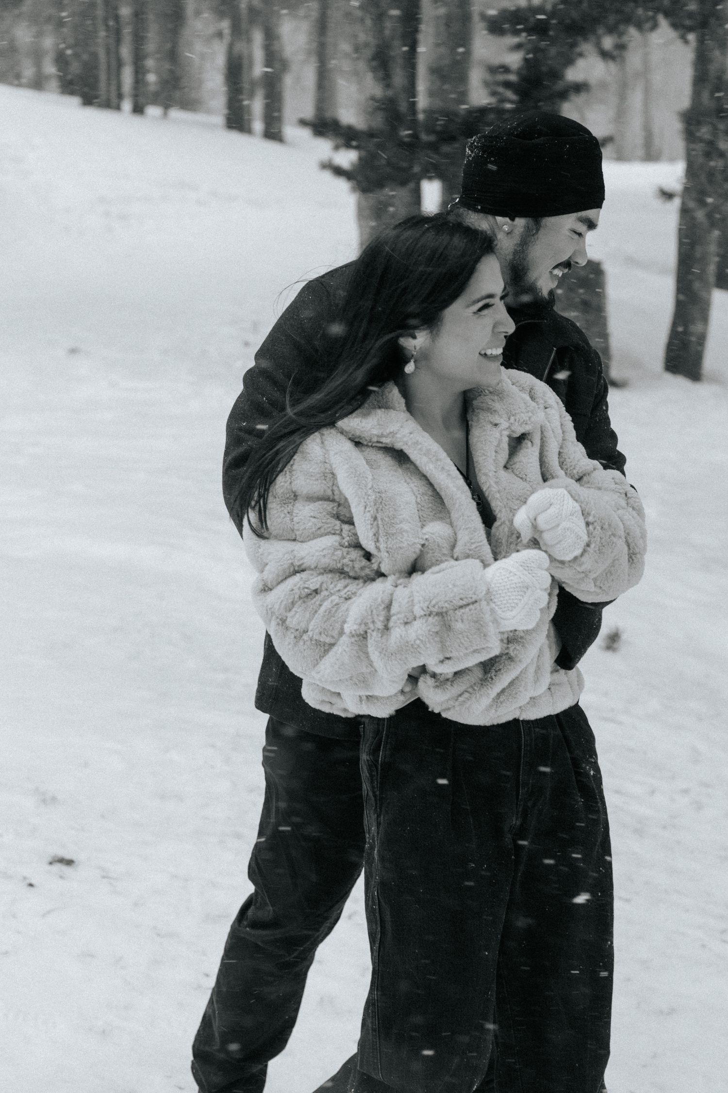 Couple sharing tender moment in winter forest surrounded by snow and pine trees.