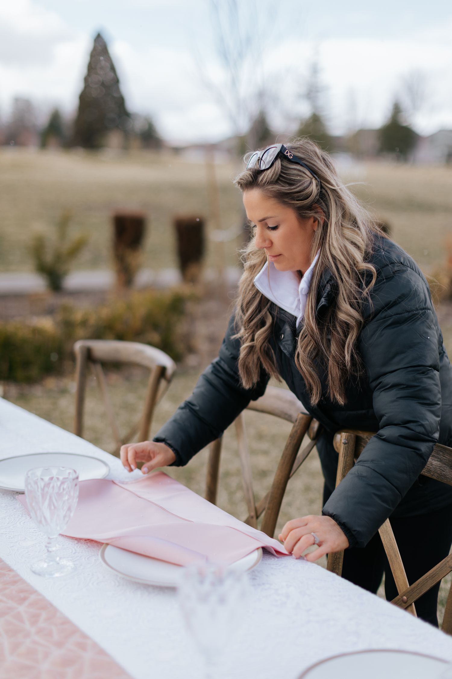 Someone writing on white paper at an outdoor table setting.