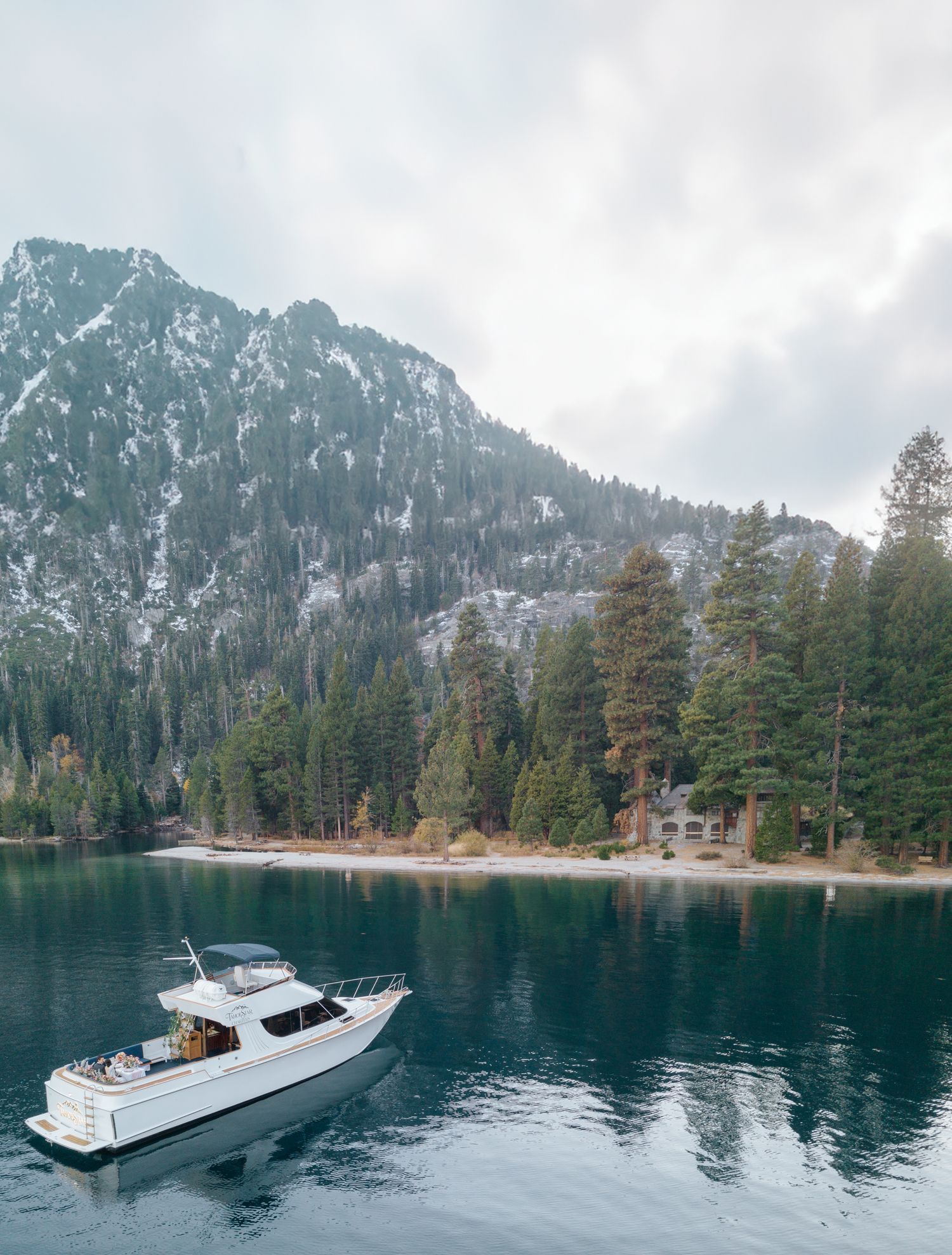 Scenic mountain lake surrounded by evergreen forest with yacht in the distance.