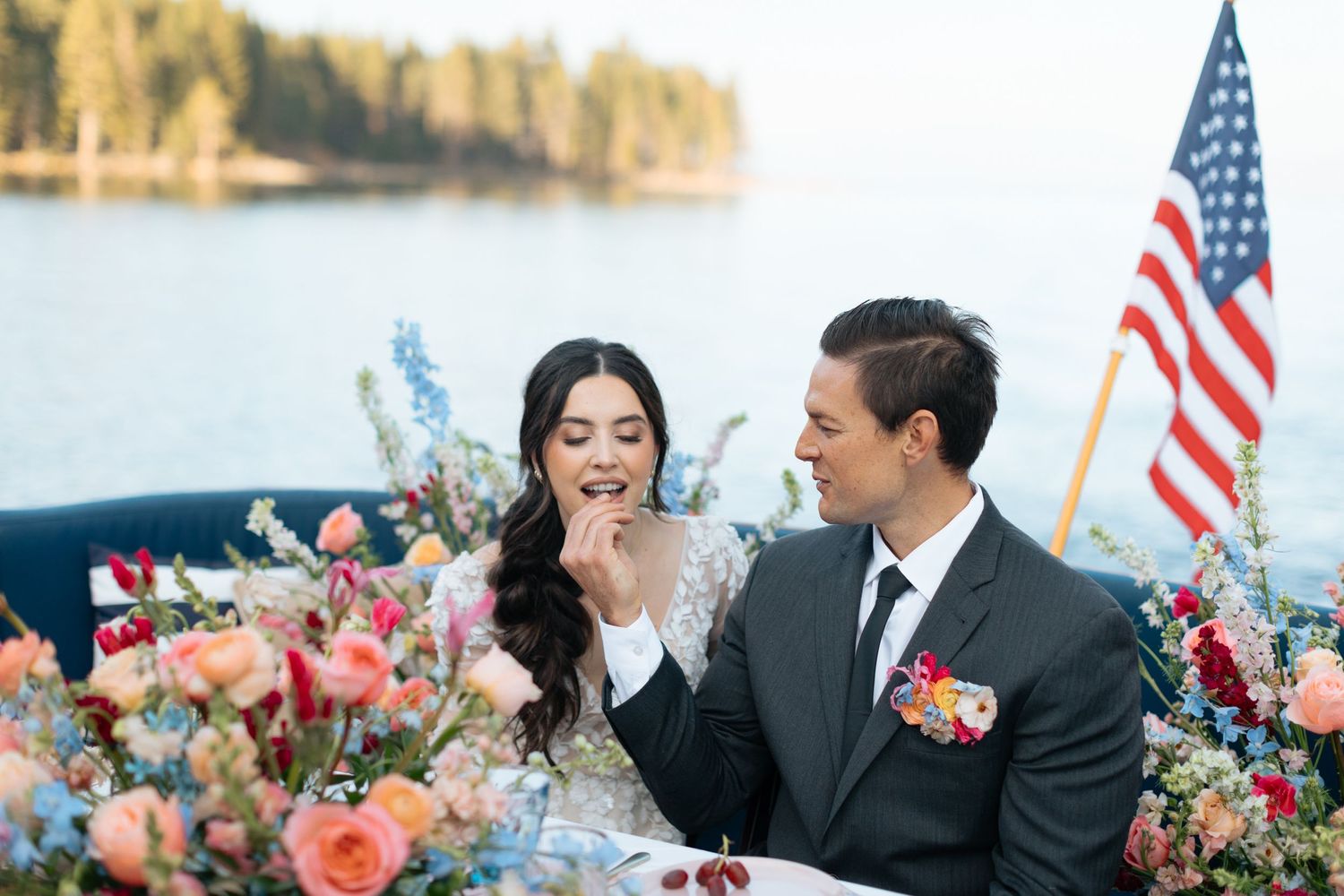 Joyful wedding celebration on boat with lake and forest backdrop.