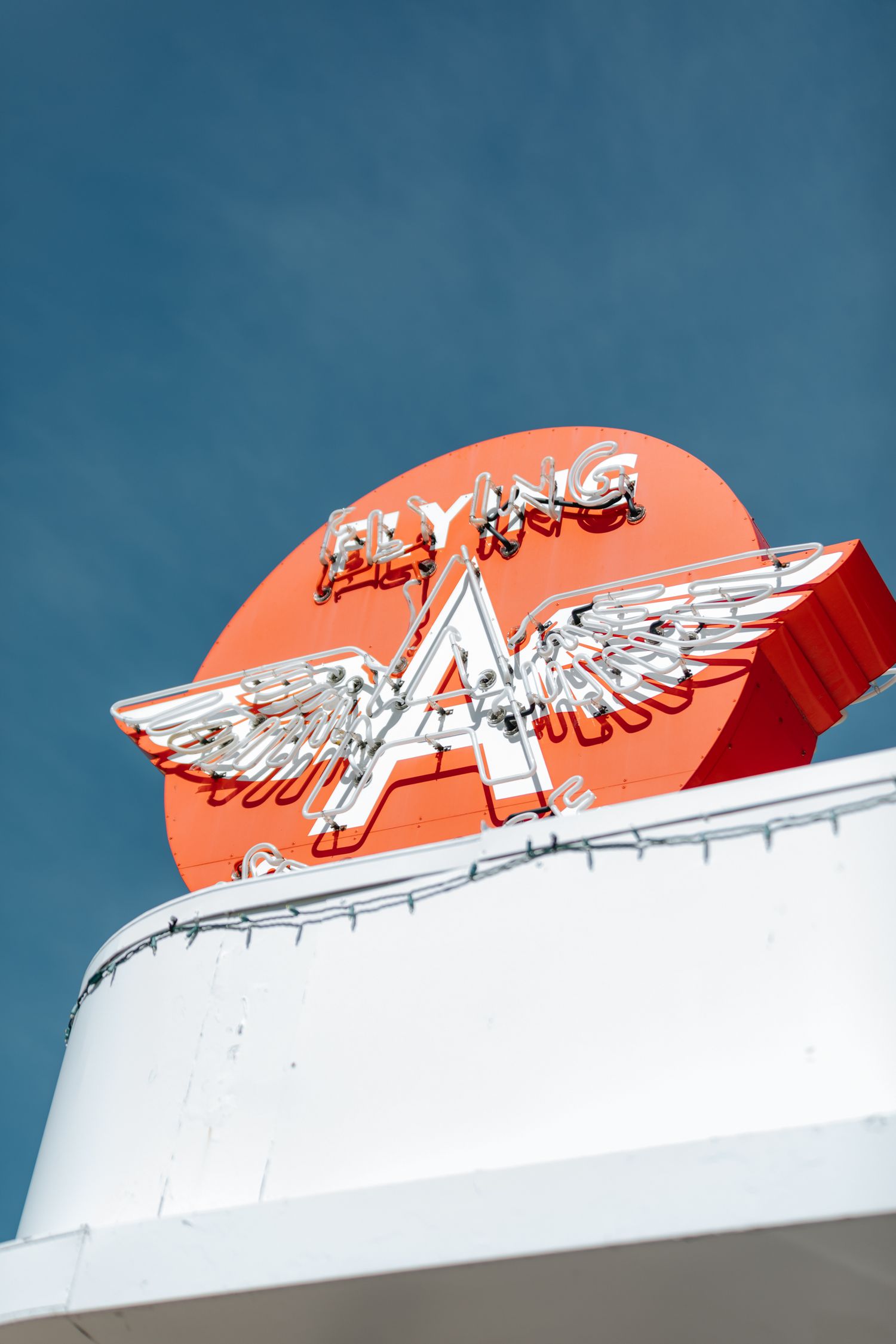 Decorative white eagle logo against orange background on building exterior.