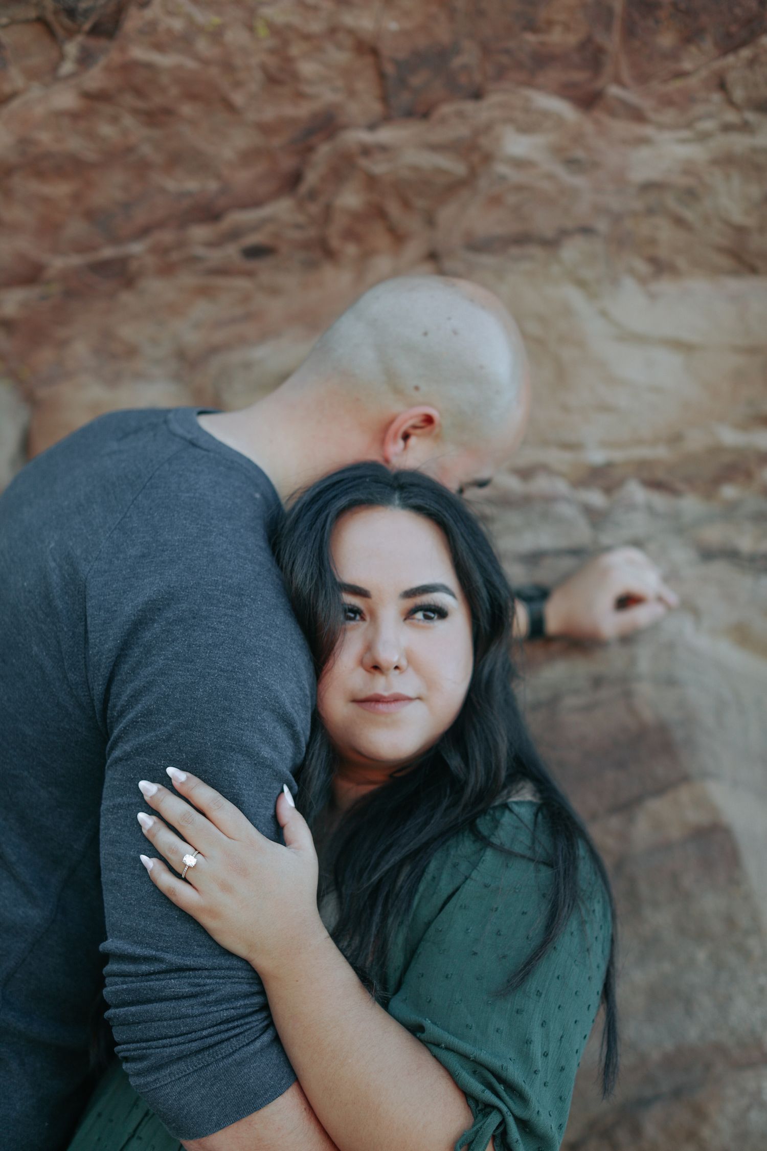 A couple embraces against a rocky desert backdrop during a romantic photoshoot.