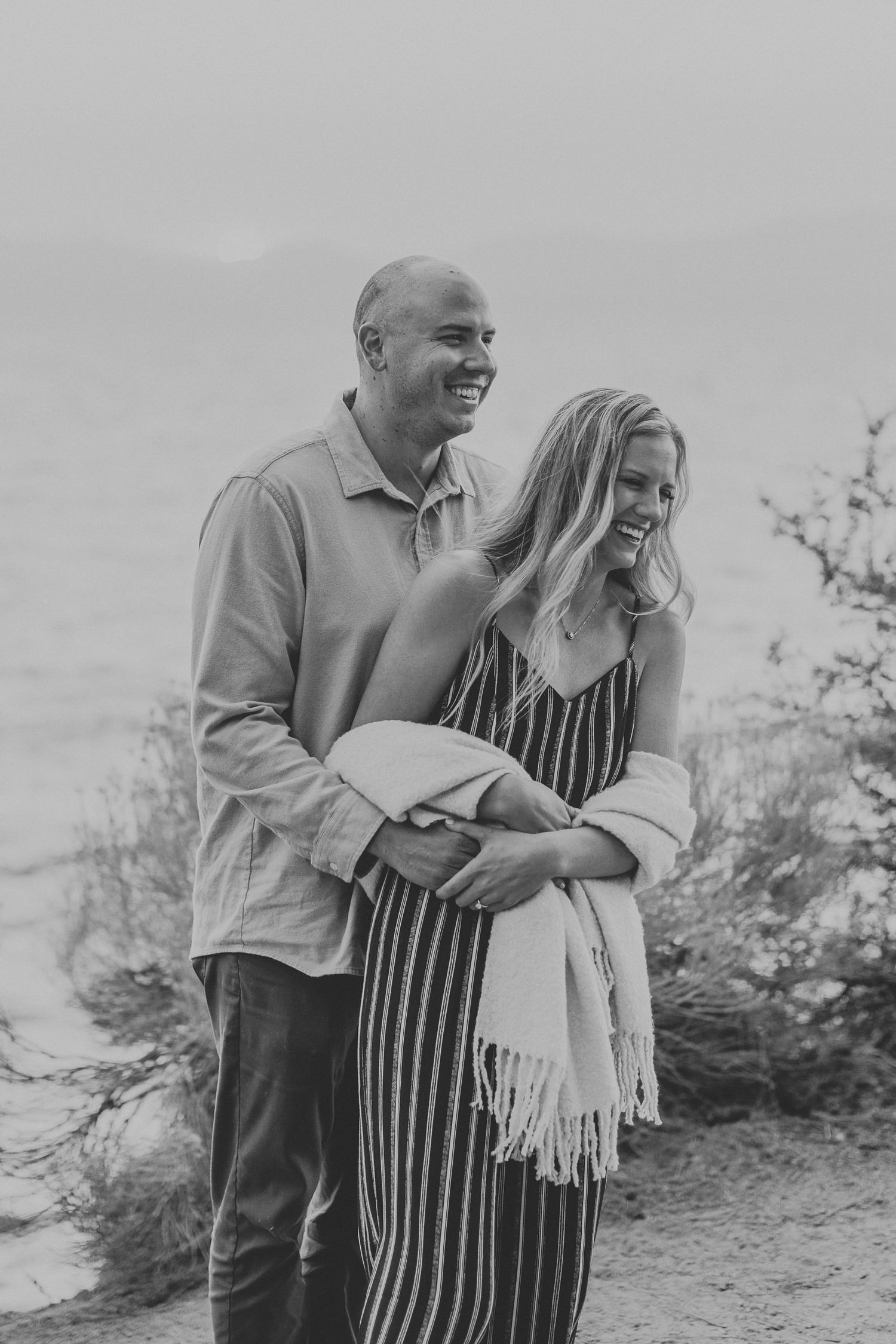 Candid black and white photo of a couple laughing together outdoors.