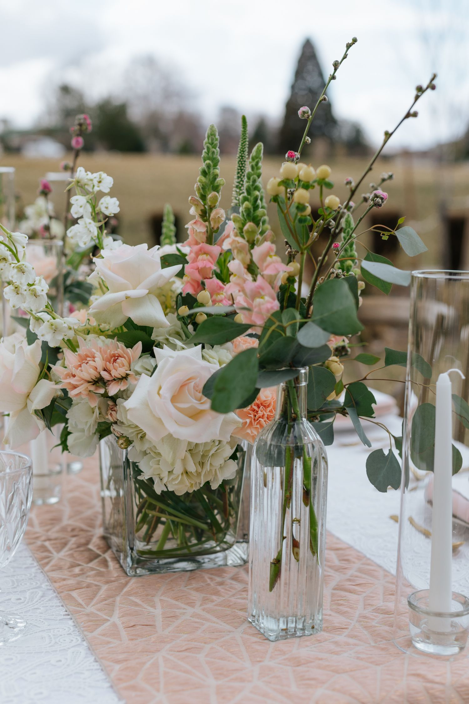 Wedding reception table decorated with pink and white floral arrangements in glass vases.