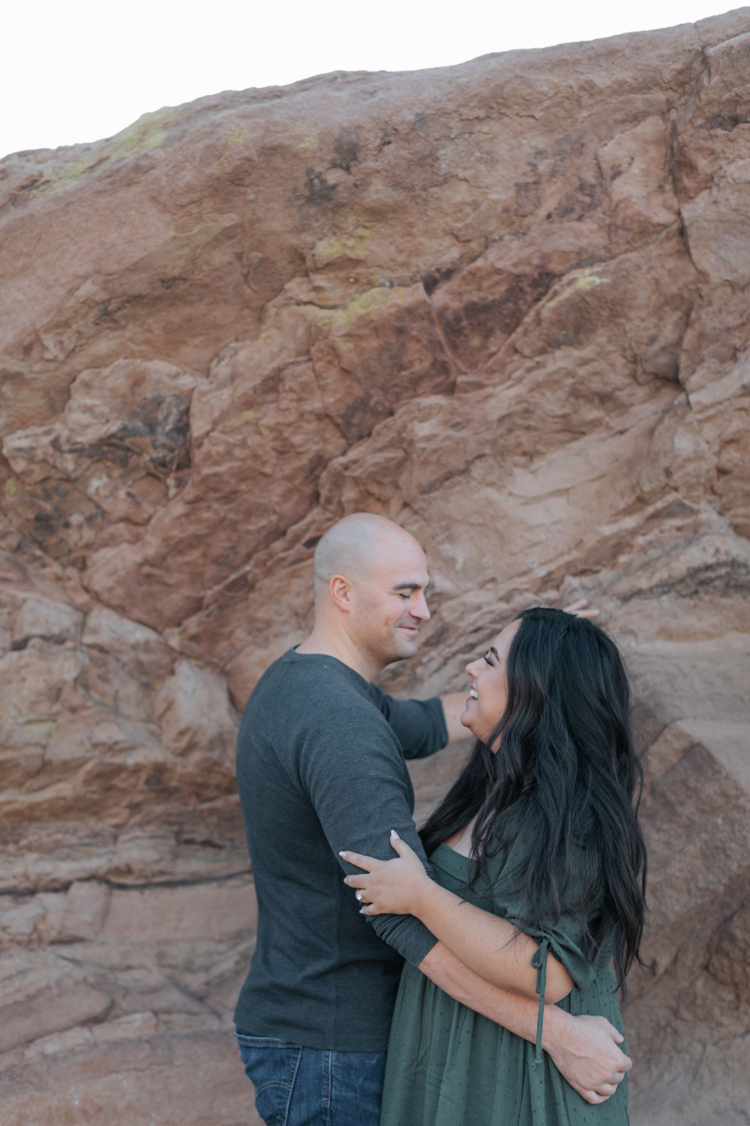 A romantic couple shares tender moments while posing near desert cliffs.