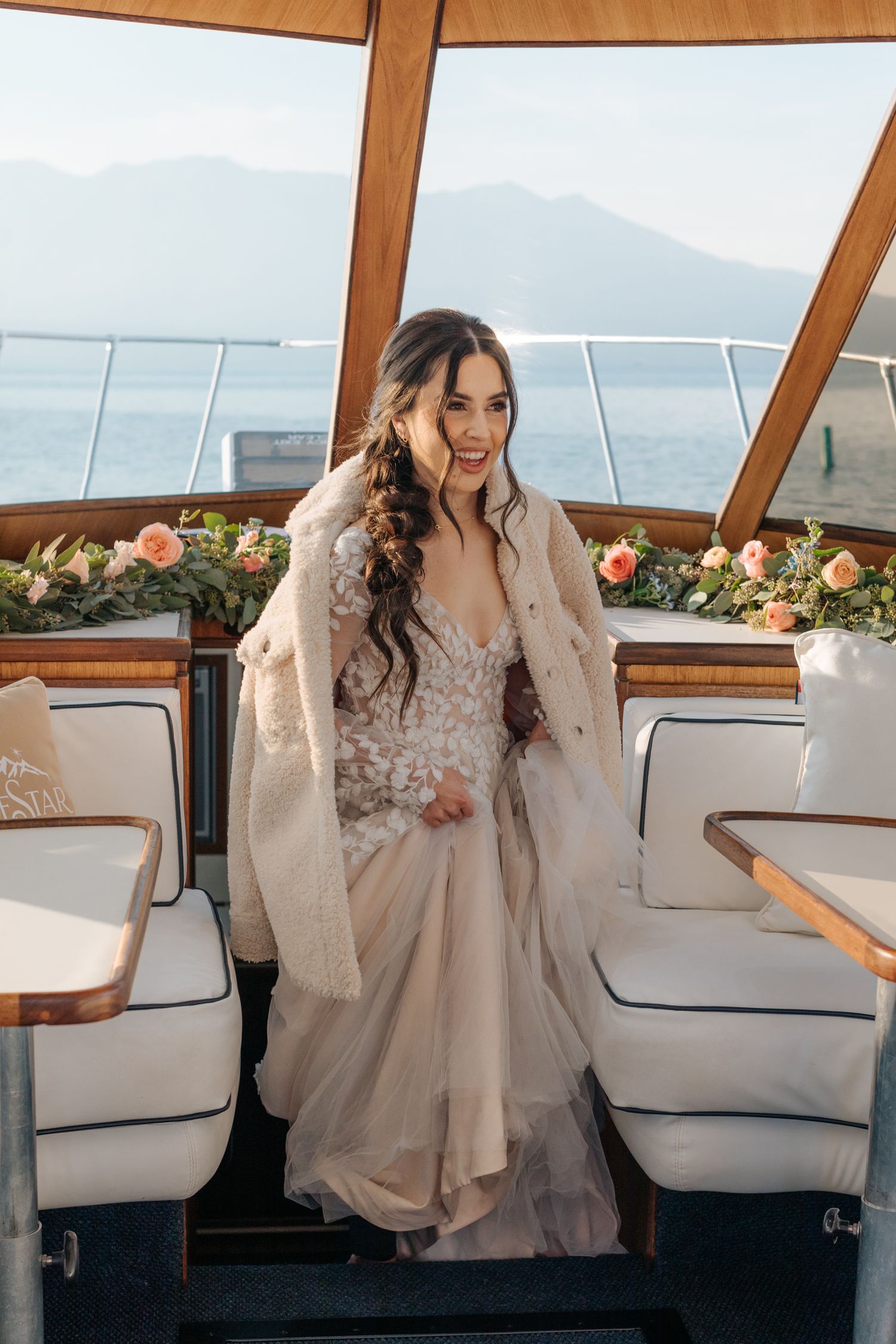 Elegant bridal setting aboard a yacht with floral decorations and mountain views.