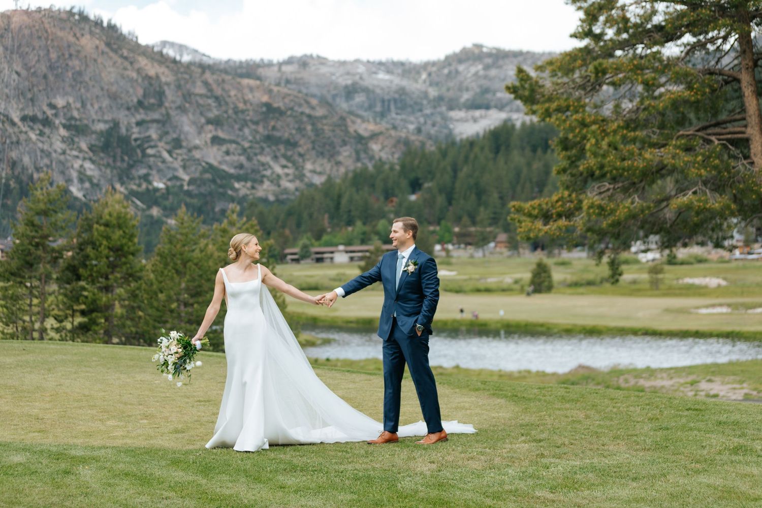 Scenic mountain wedding photos with couple walking across grassy field.