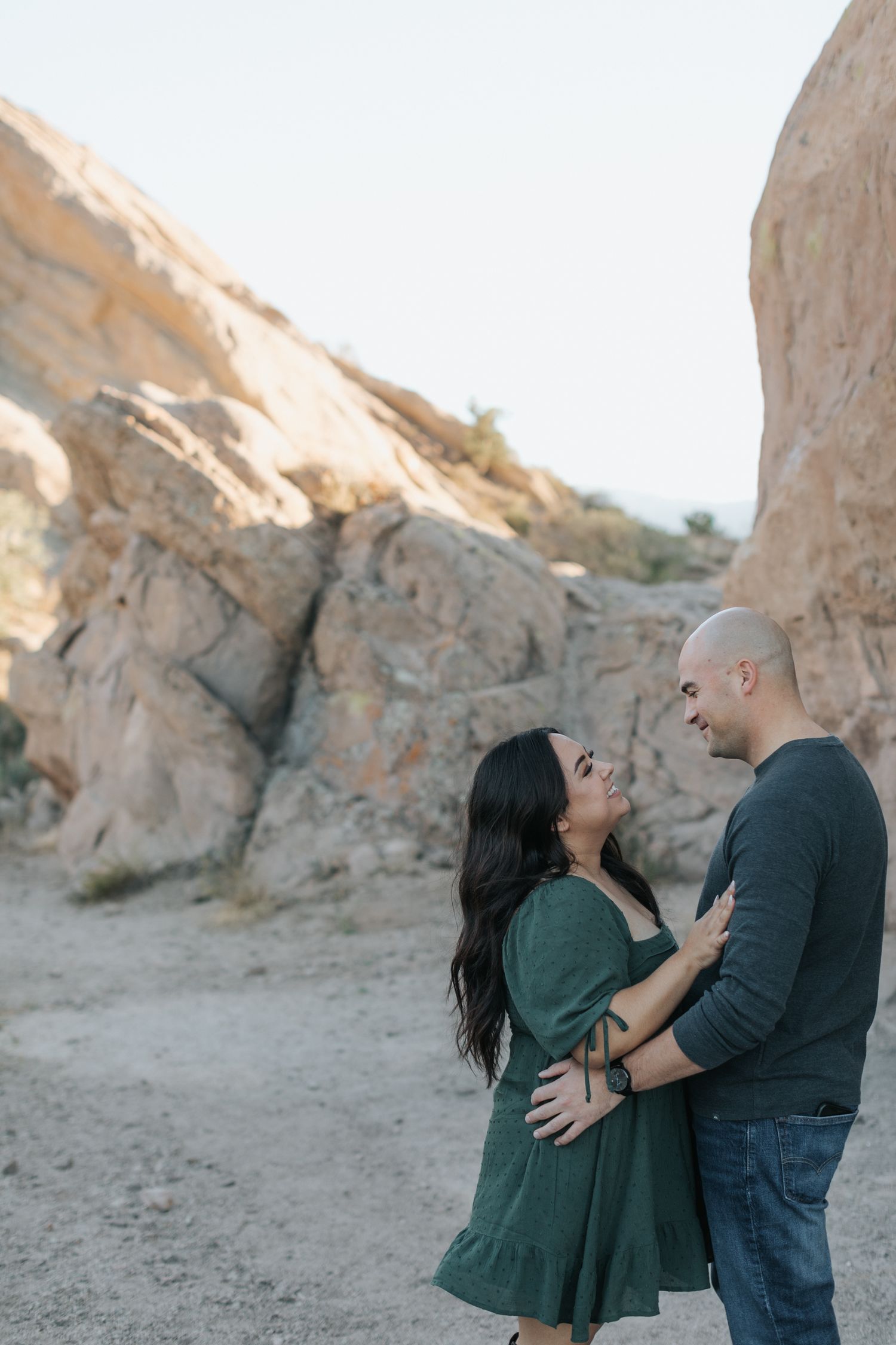 Couple sharing joyful moments against rocky desert landscape during sunset.