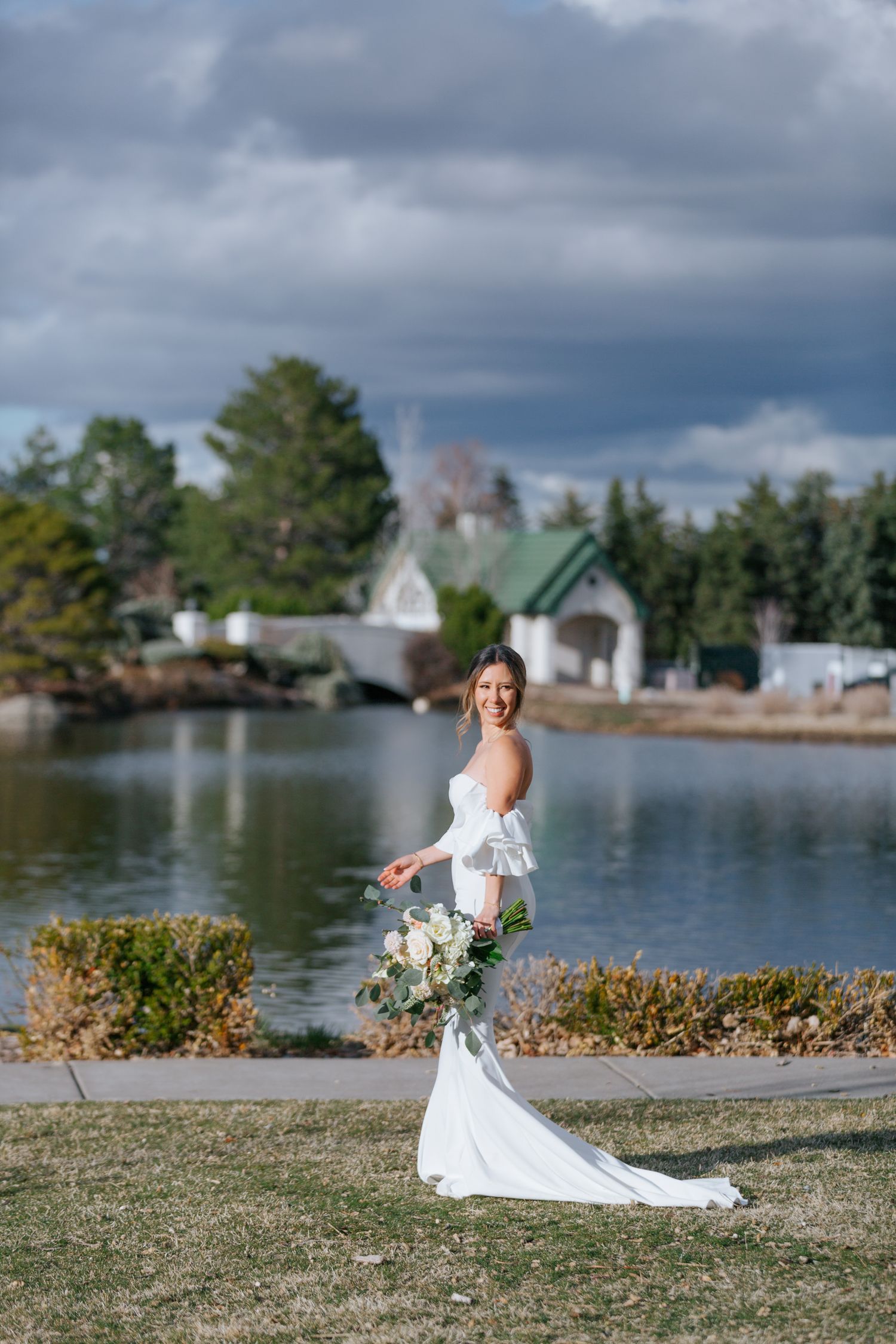 A sequence of photos showing someone in a flowing white wedding dress posing gracefully by a lakeside on a cloudy day.