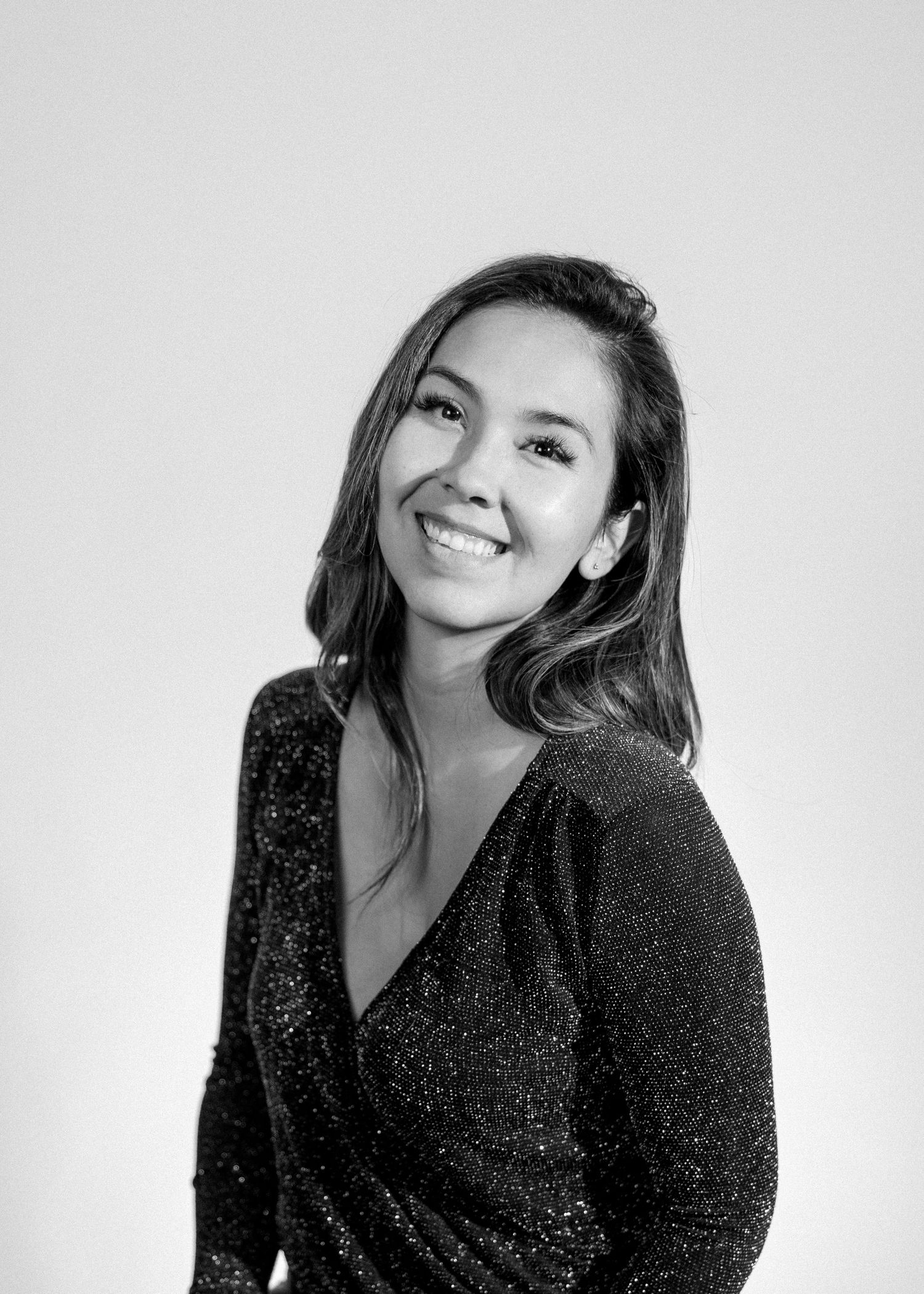 A person in a black sparkly dress poses against a white background in a series of candid shots.
