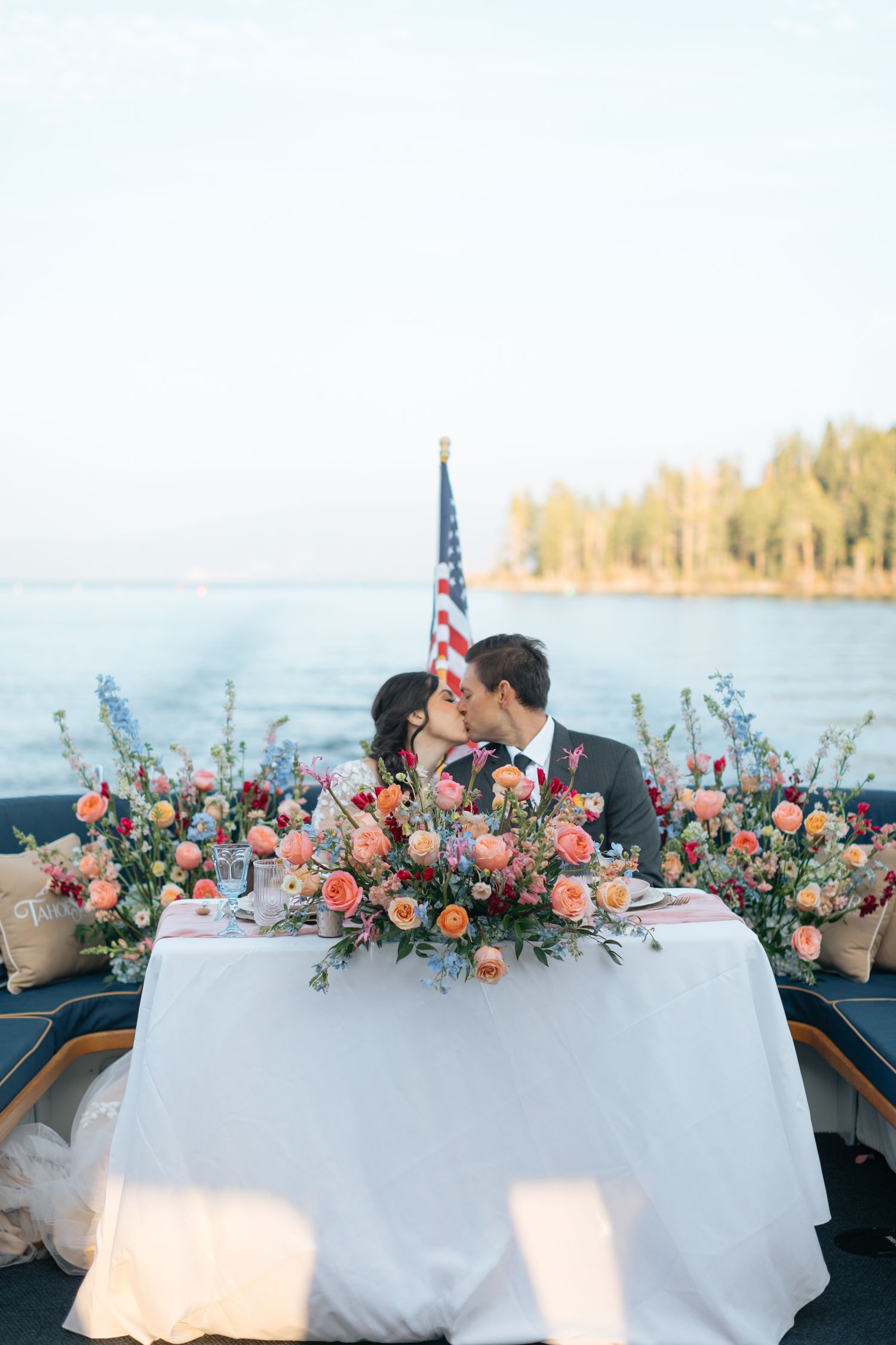 Wedding table setup on a boat deck with floral centerpieces and an American flag.